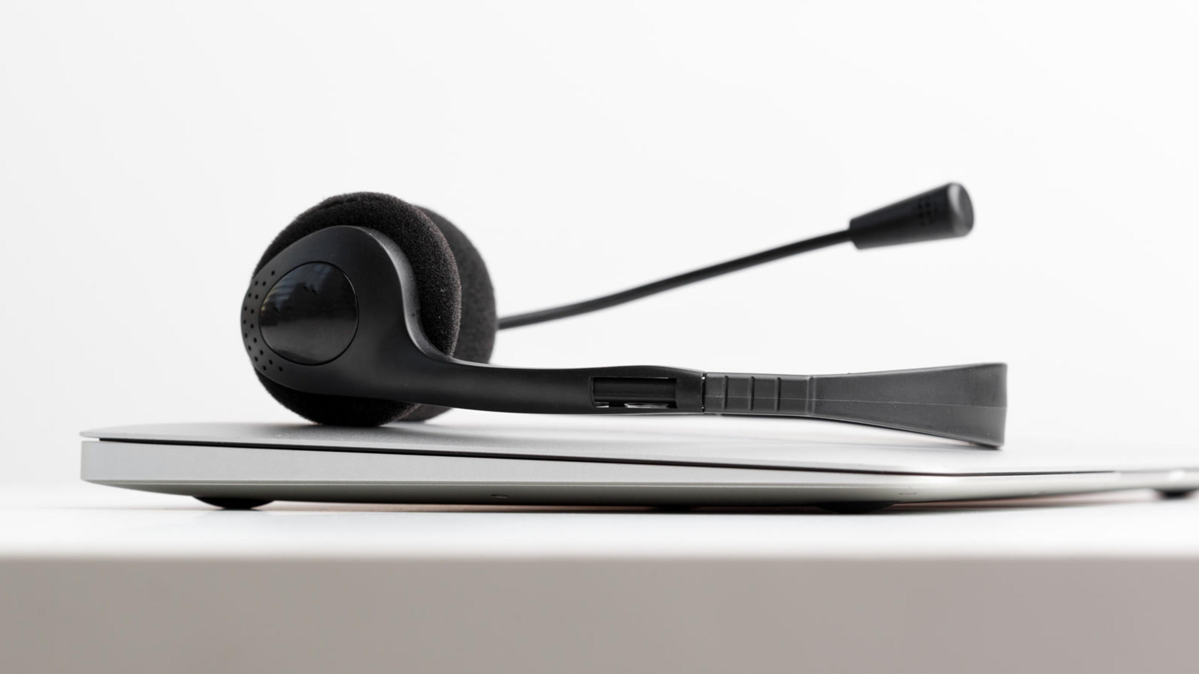 Black support headset resting on a closed laptop — help desk and softphone support tools