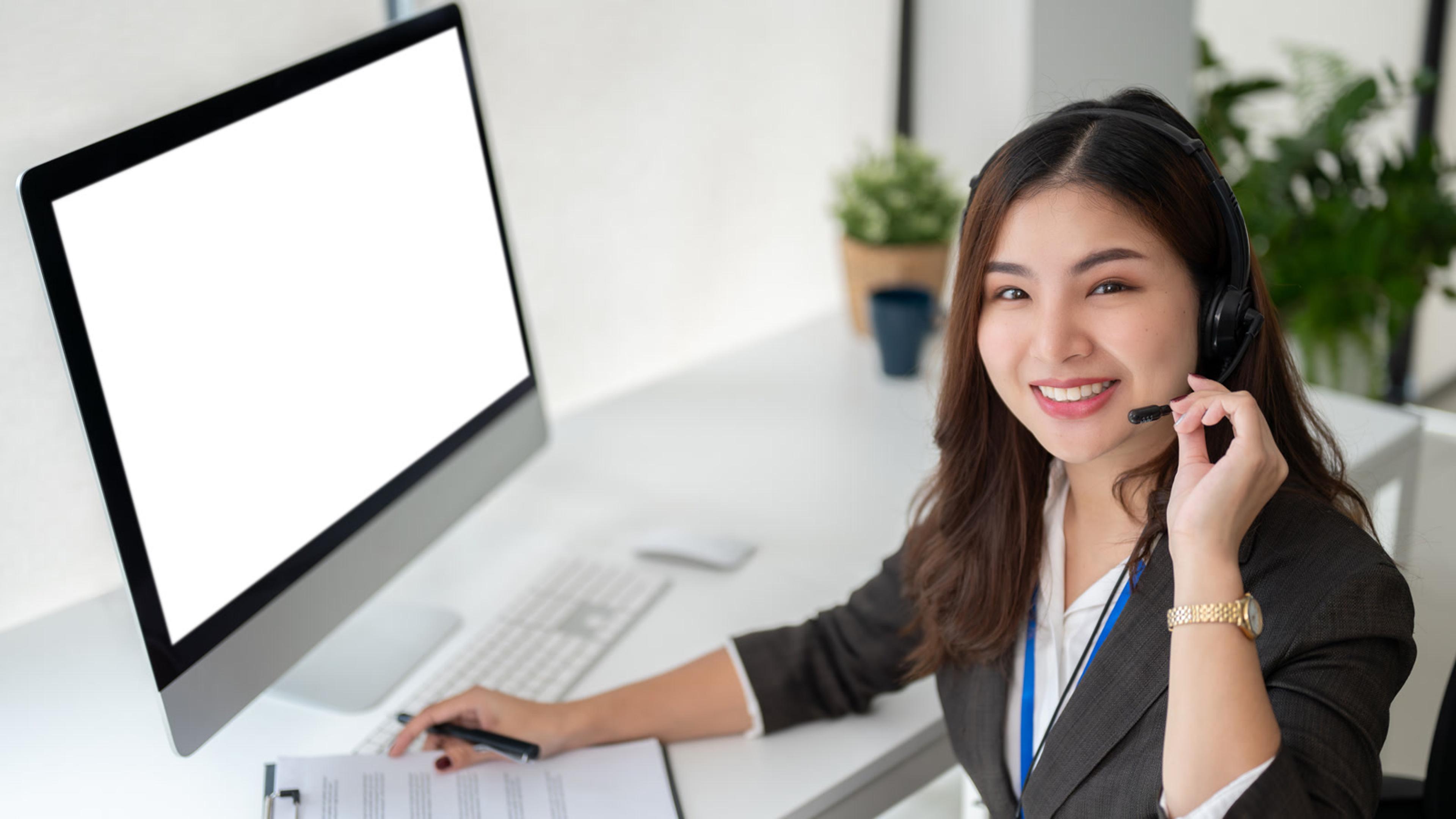 Smiling woman working at a computer with headset during FreePBX softphone setup