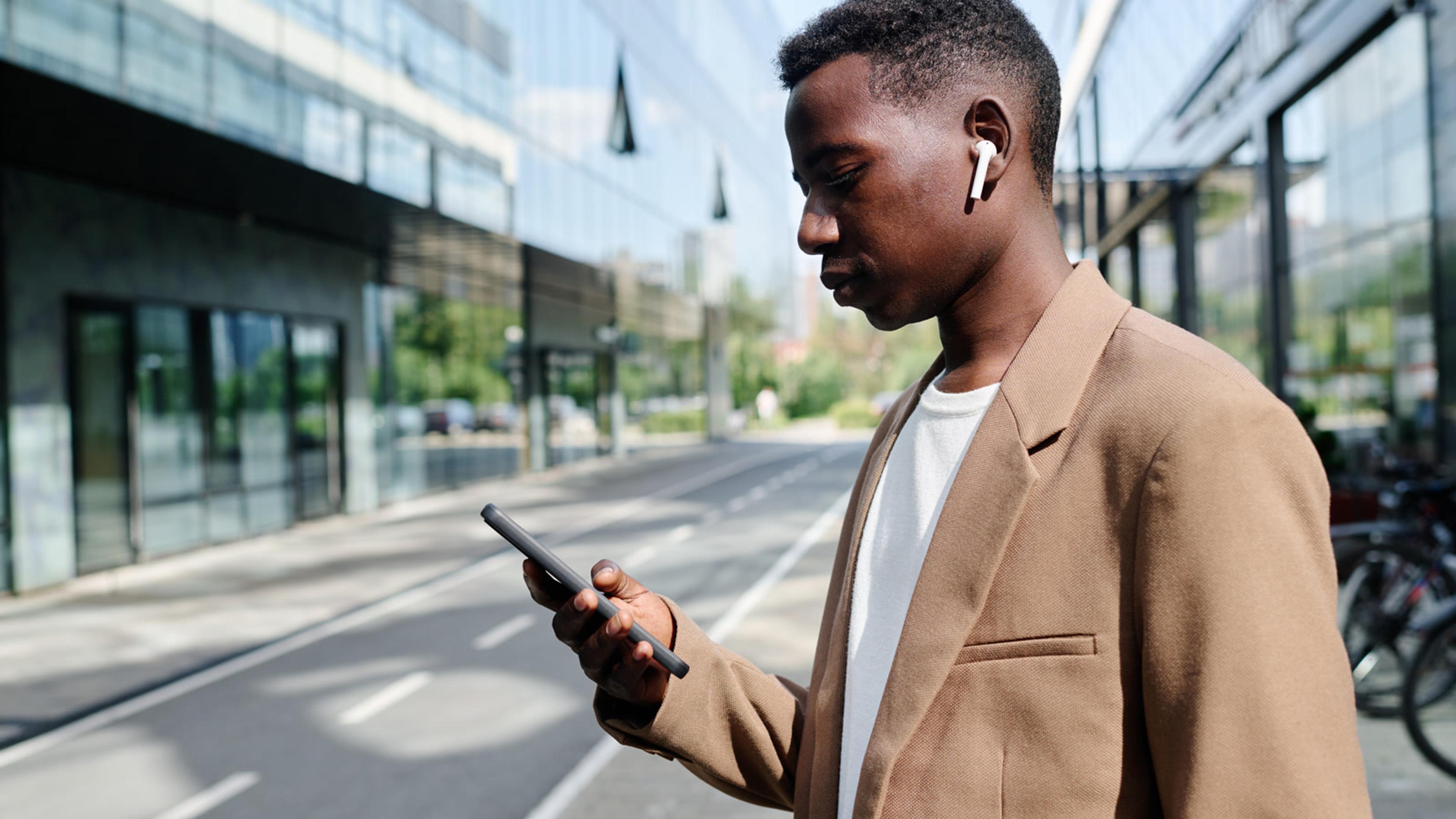 Stylish man using phone outside modern office — FusionPBX mobile softphones