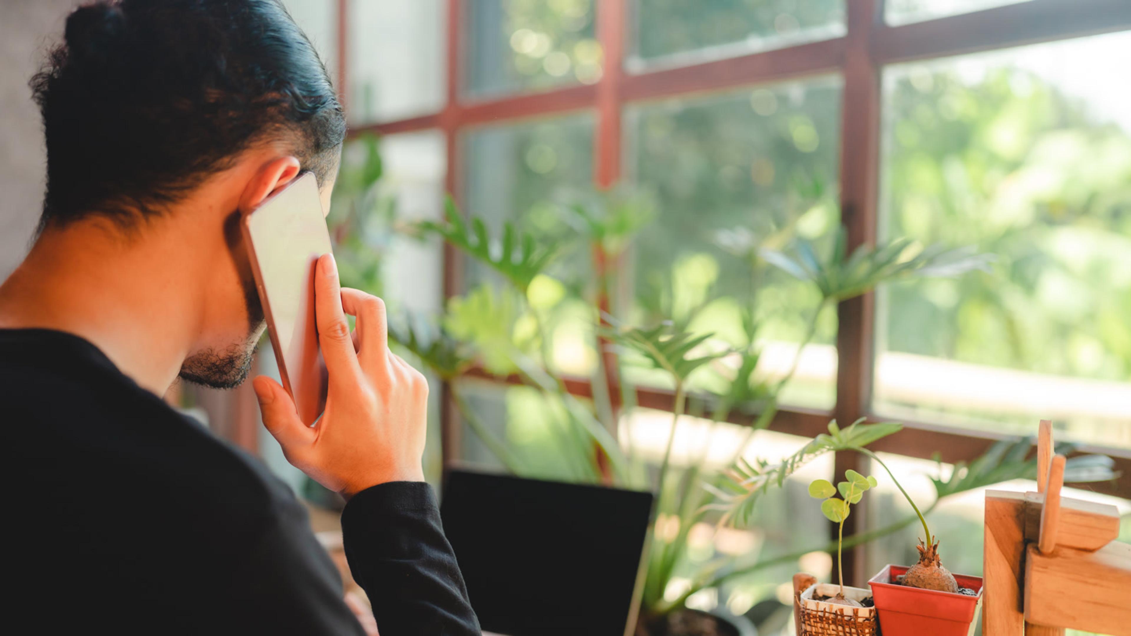 Adult using a phone and laptop at home — mobile softphone with push notifications