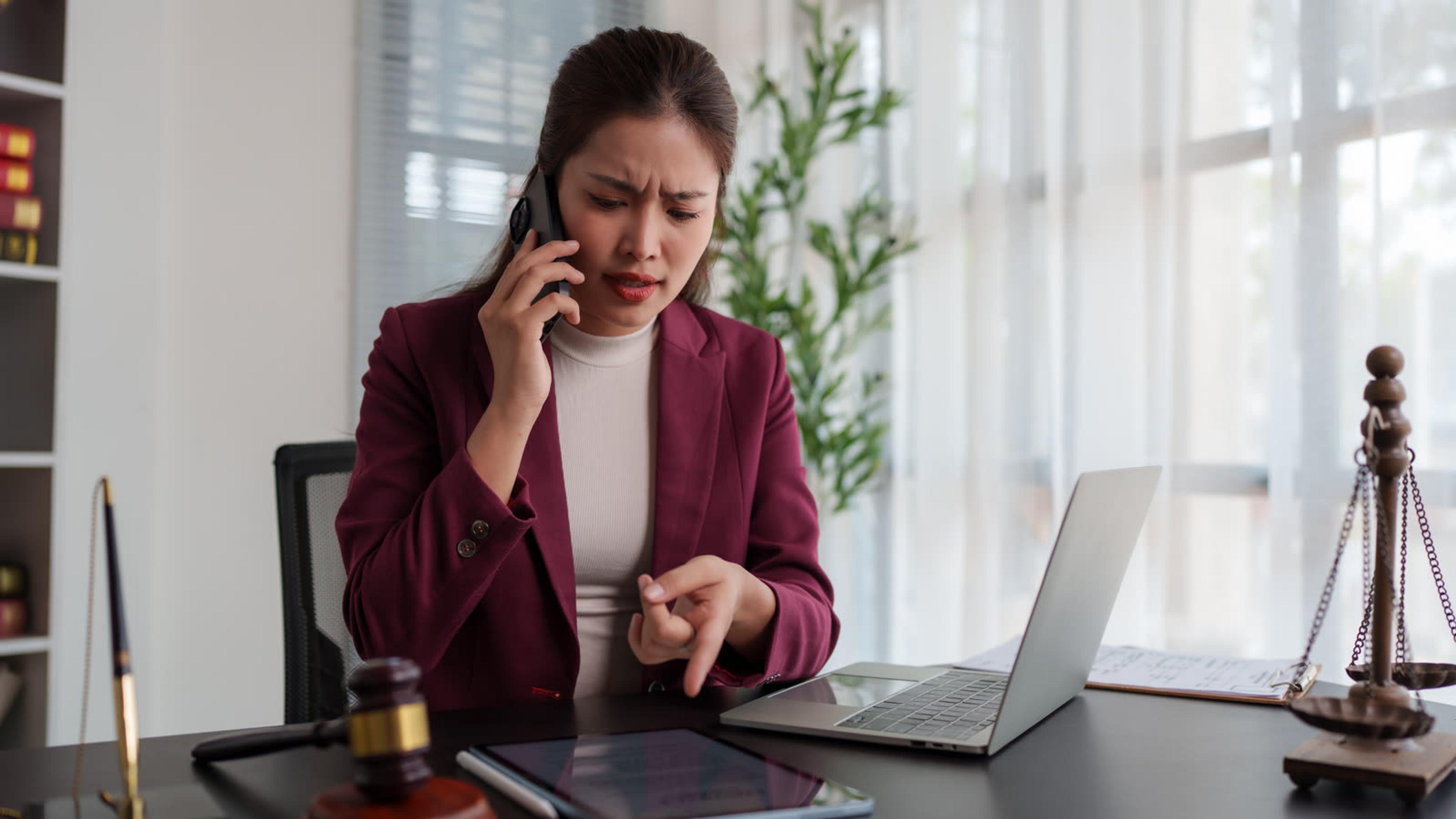 Professional on a phone call at her desk — after-hours incident response and on-call escalation