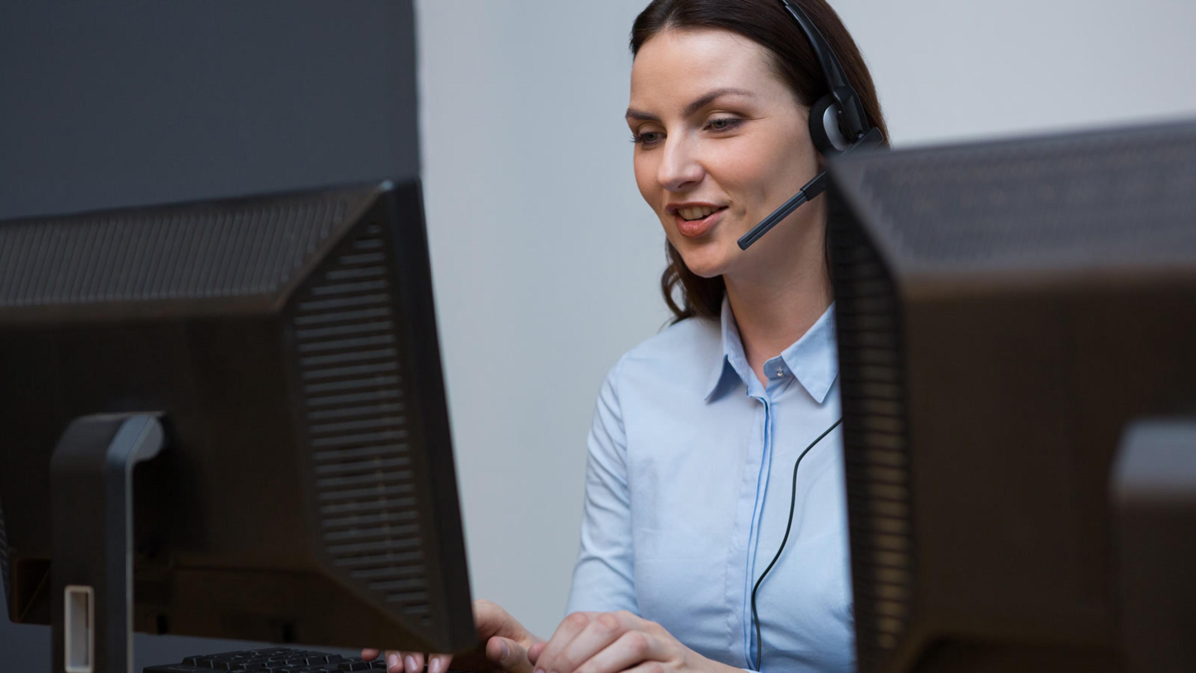 Professional woman working at computer with headset — softphones for support teams