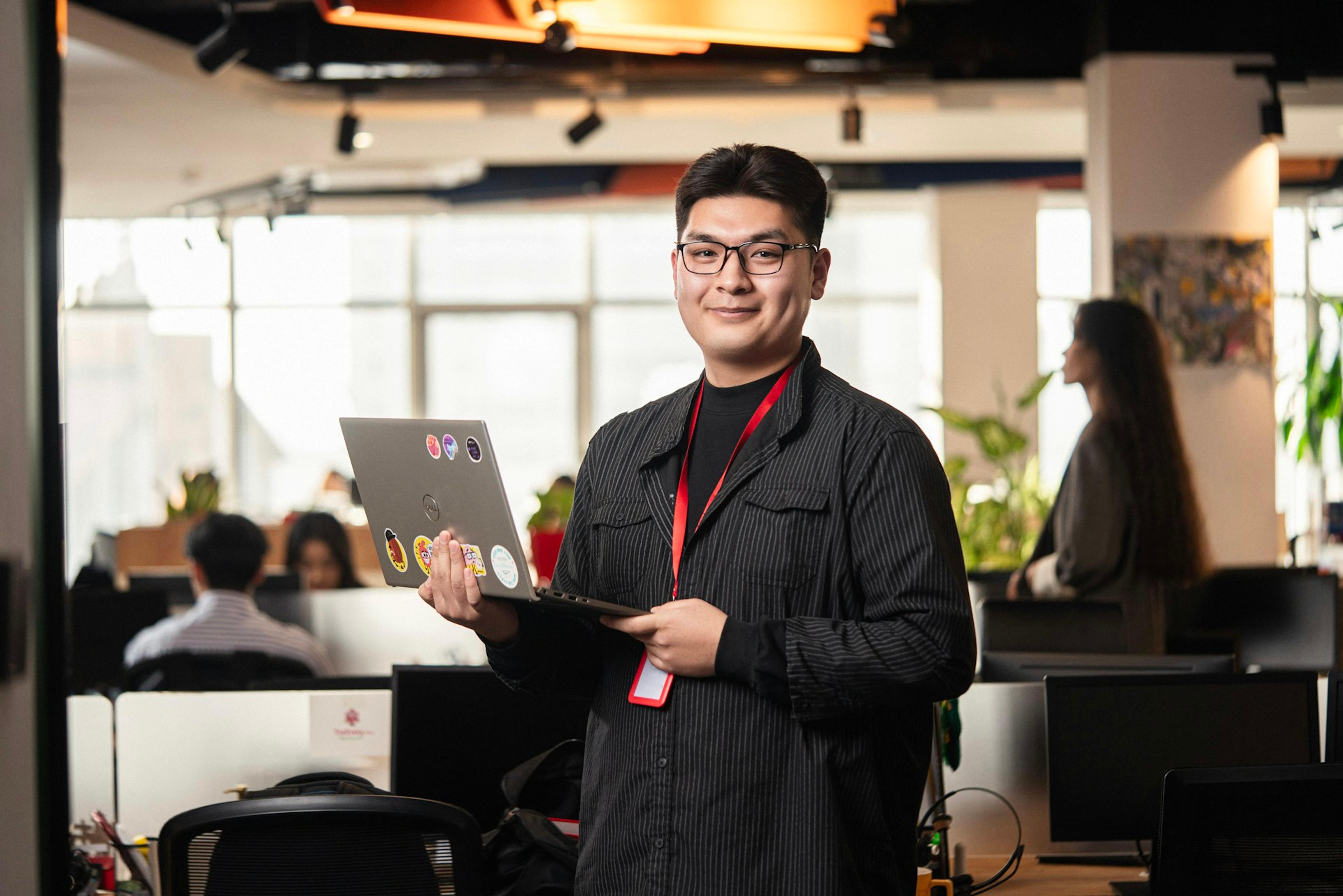 IT professional holding a laptop in a modern office, representing enterprise communications deployment at scale
