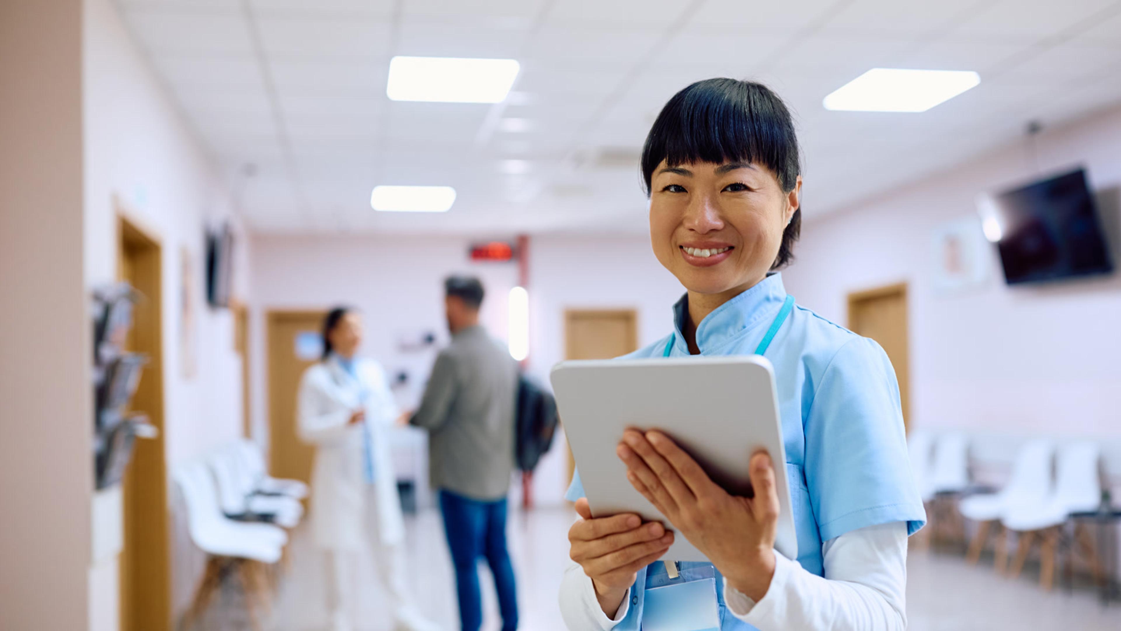 Smiling healthcare worker holding a tablet in a hospital setting