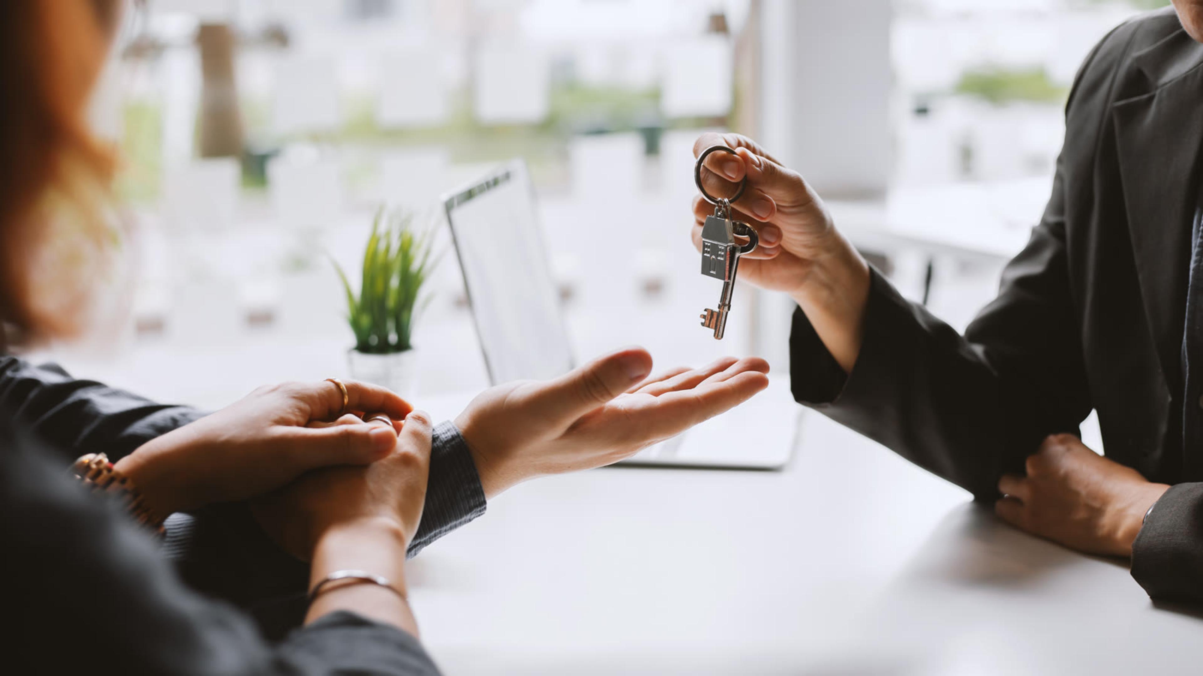 Real estate professional handing over new house keys after a property deal