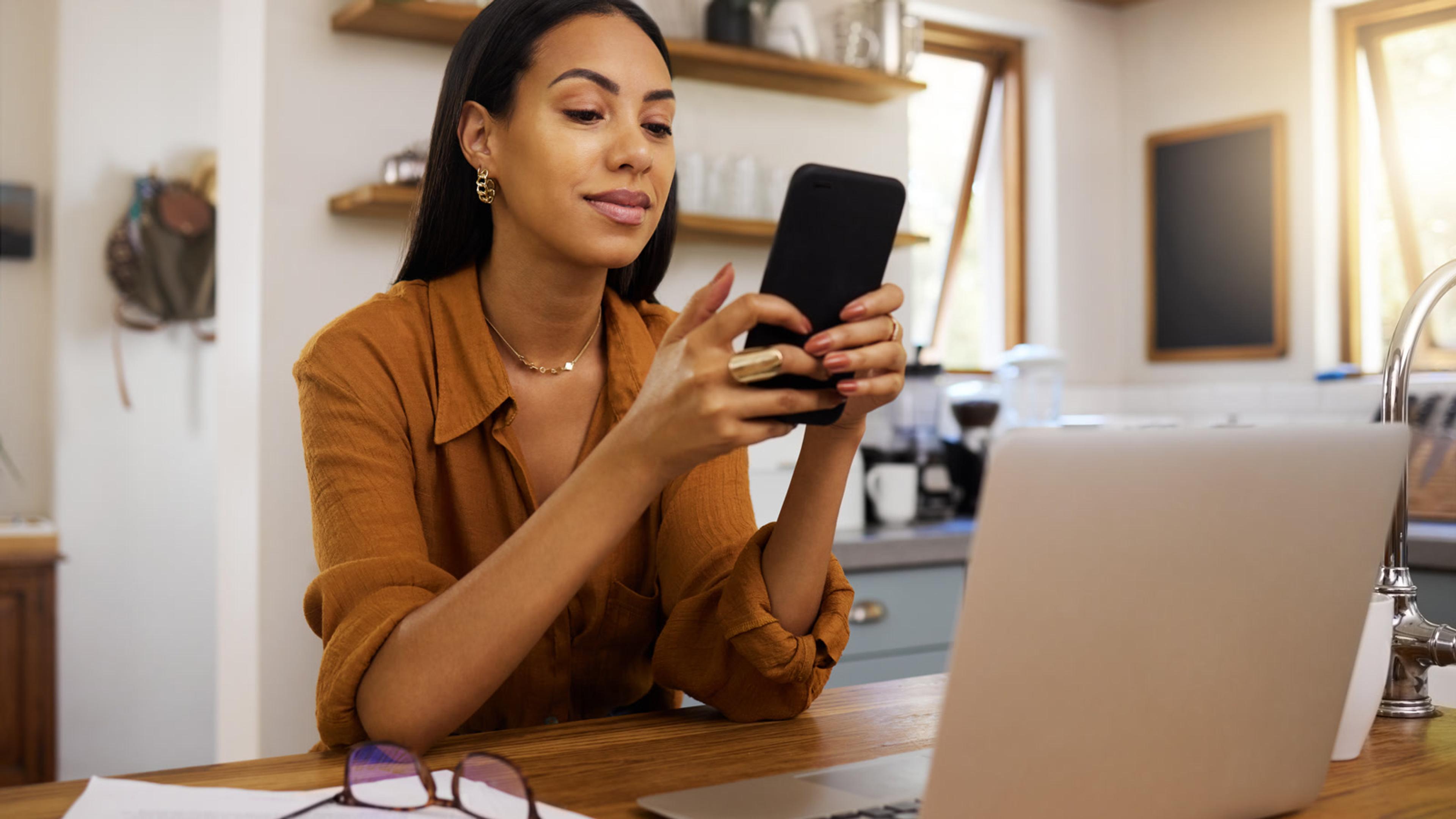 Woman working at home using smartphone and laptop — FusionPBX mobile softphones