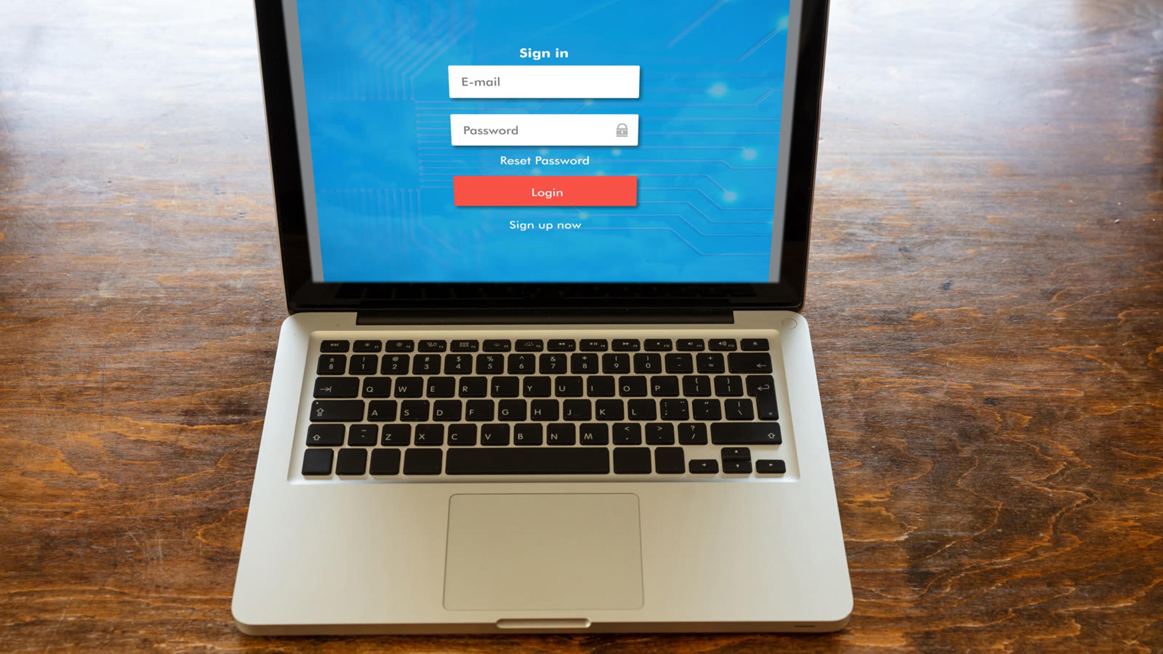 Laptop on a wooden desk showing a username and password login screen for a business system