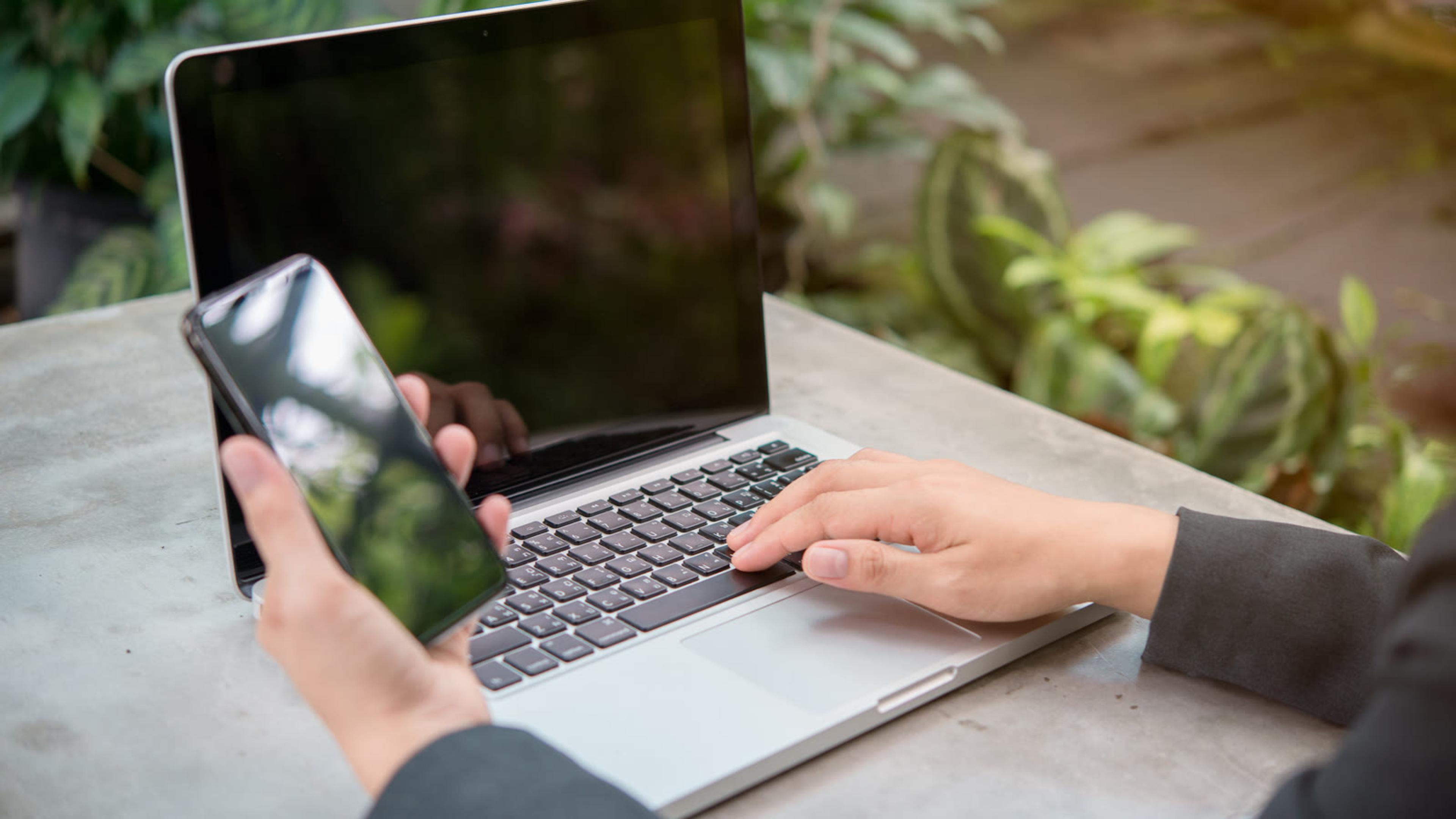 Professional working remotely with a laptop and smartphone for client calls