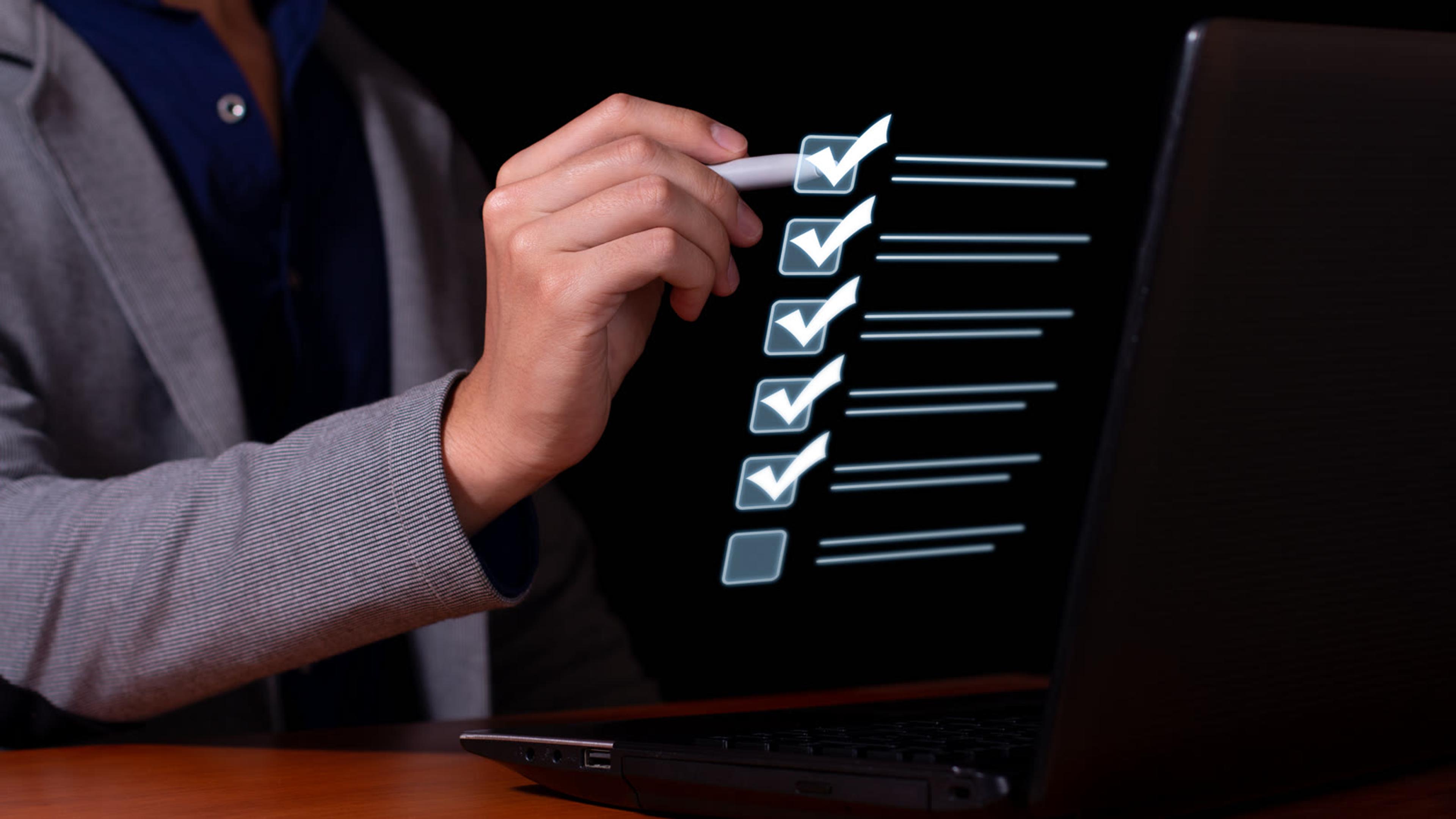 Person ticking items off a checklist on a laptop