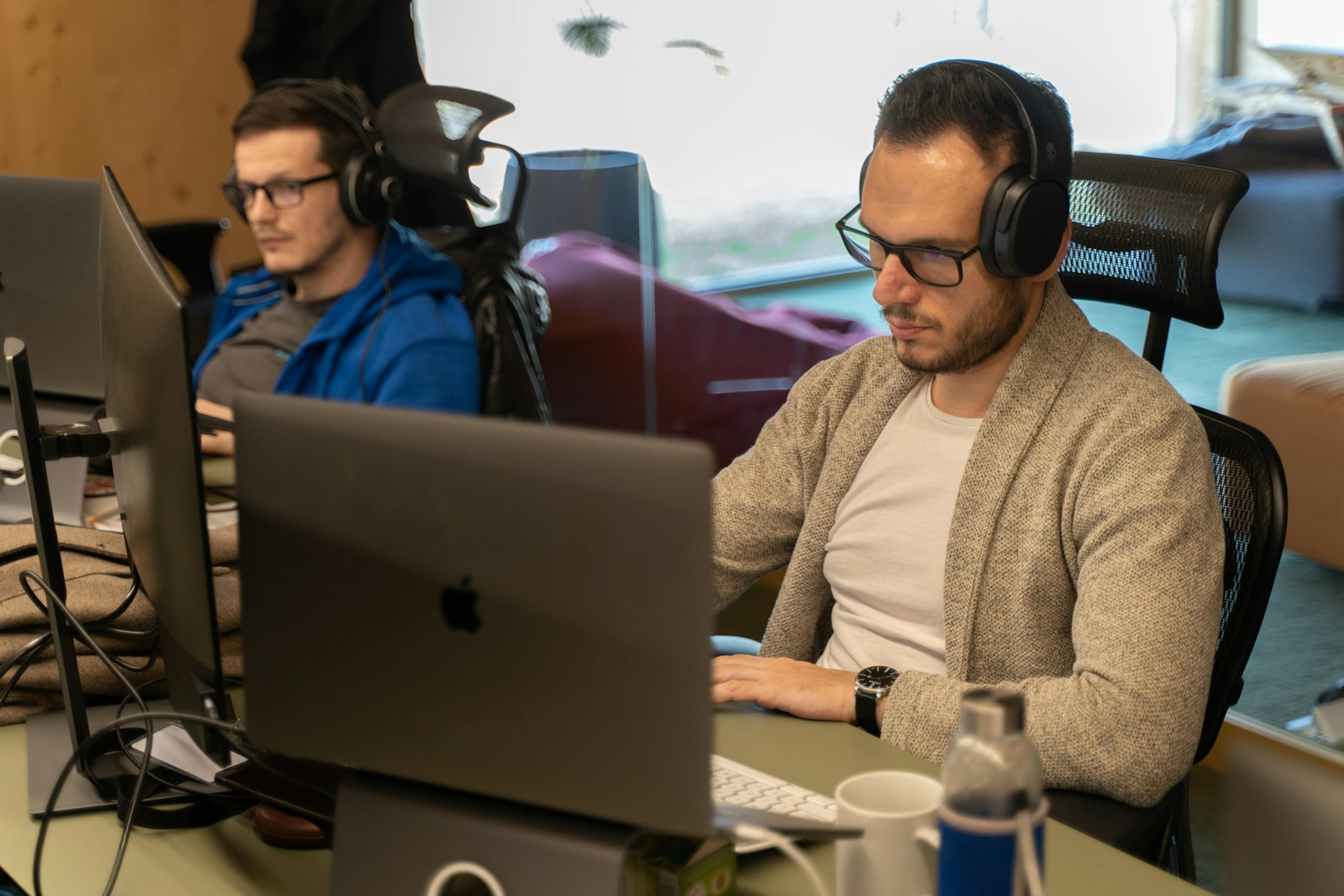 Office employees wearing headsets while testing calls on laptop computers