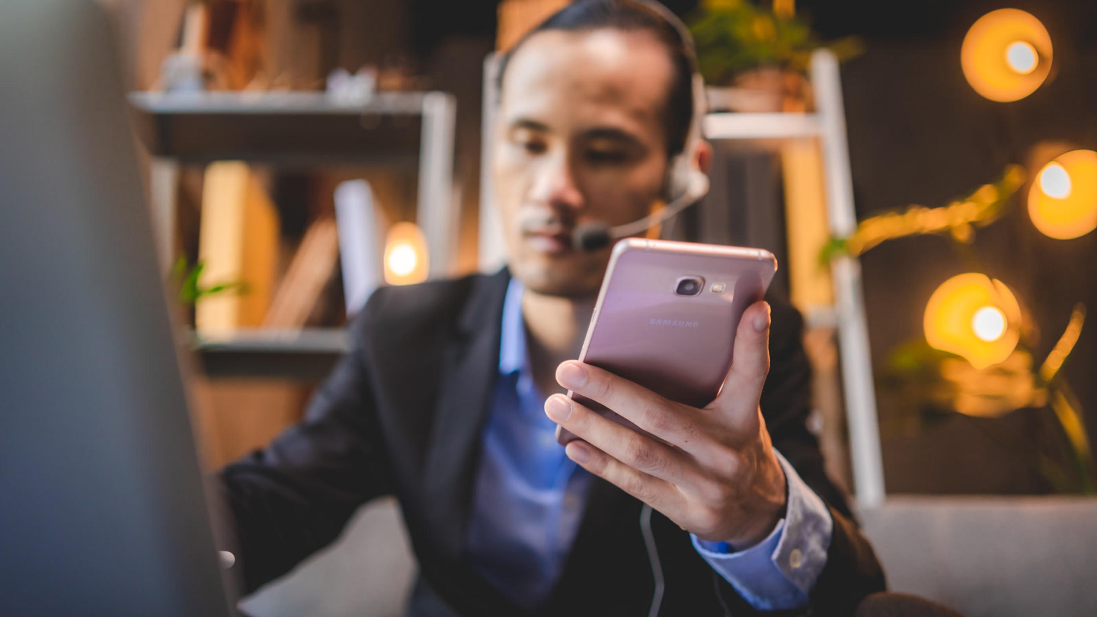 Man working with a phone and laptop for business — ITSP office VoIP softphone lifestyle