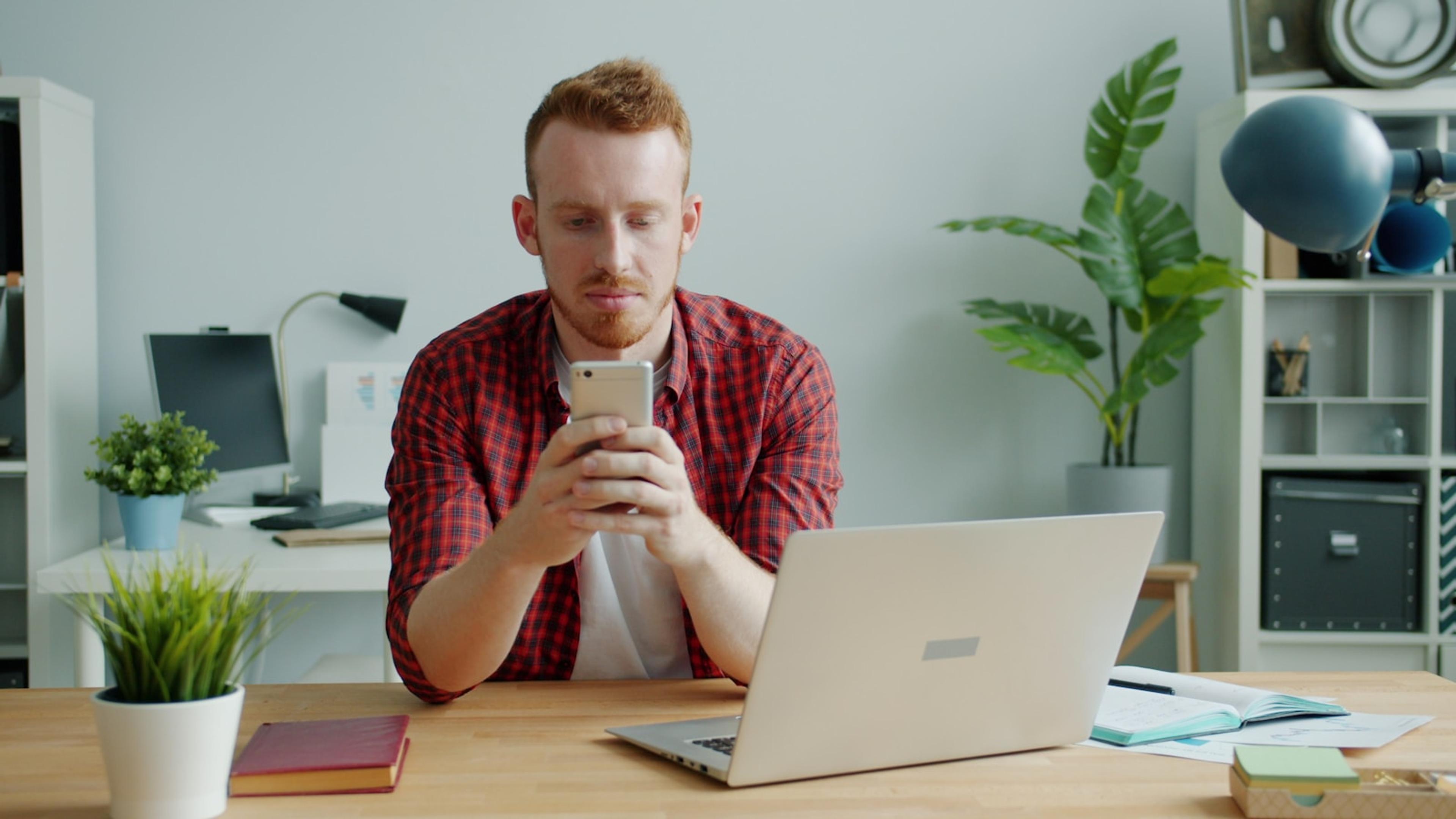 Business user validating mobile calling beside a laptop in an office
