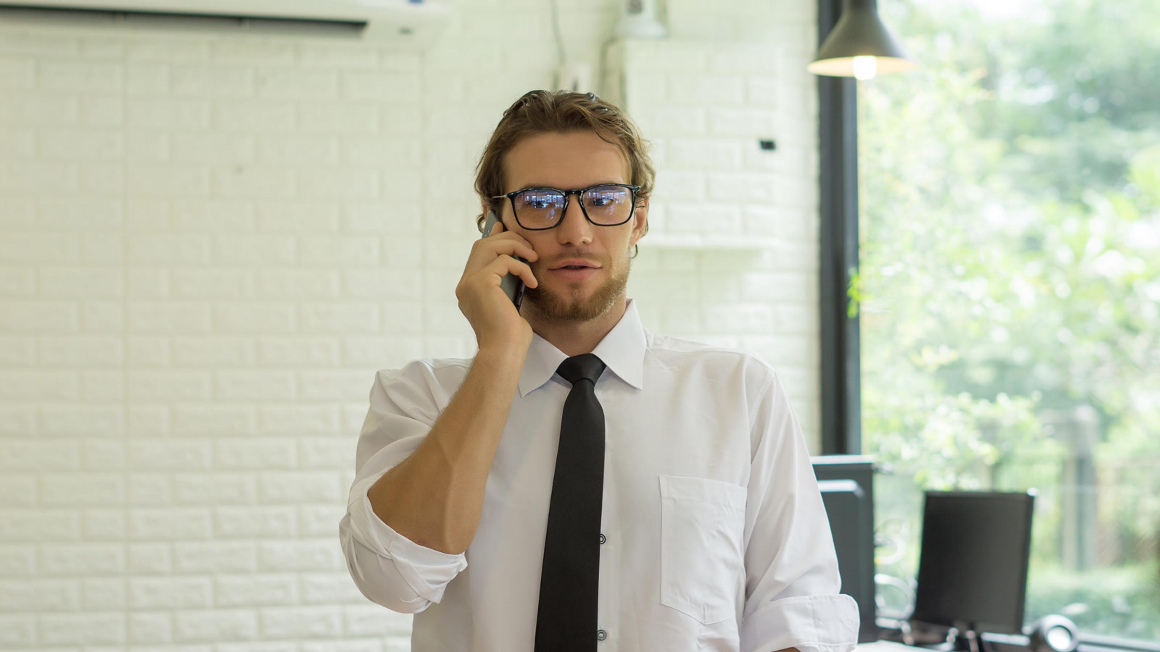 Man in shirt and tie talking on the phone after porting a business number