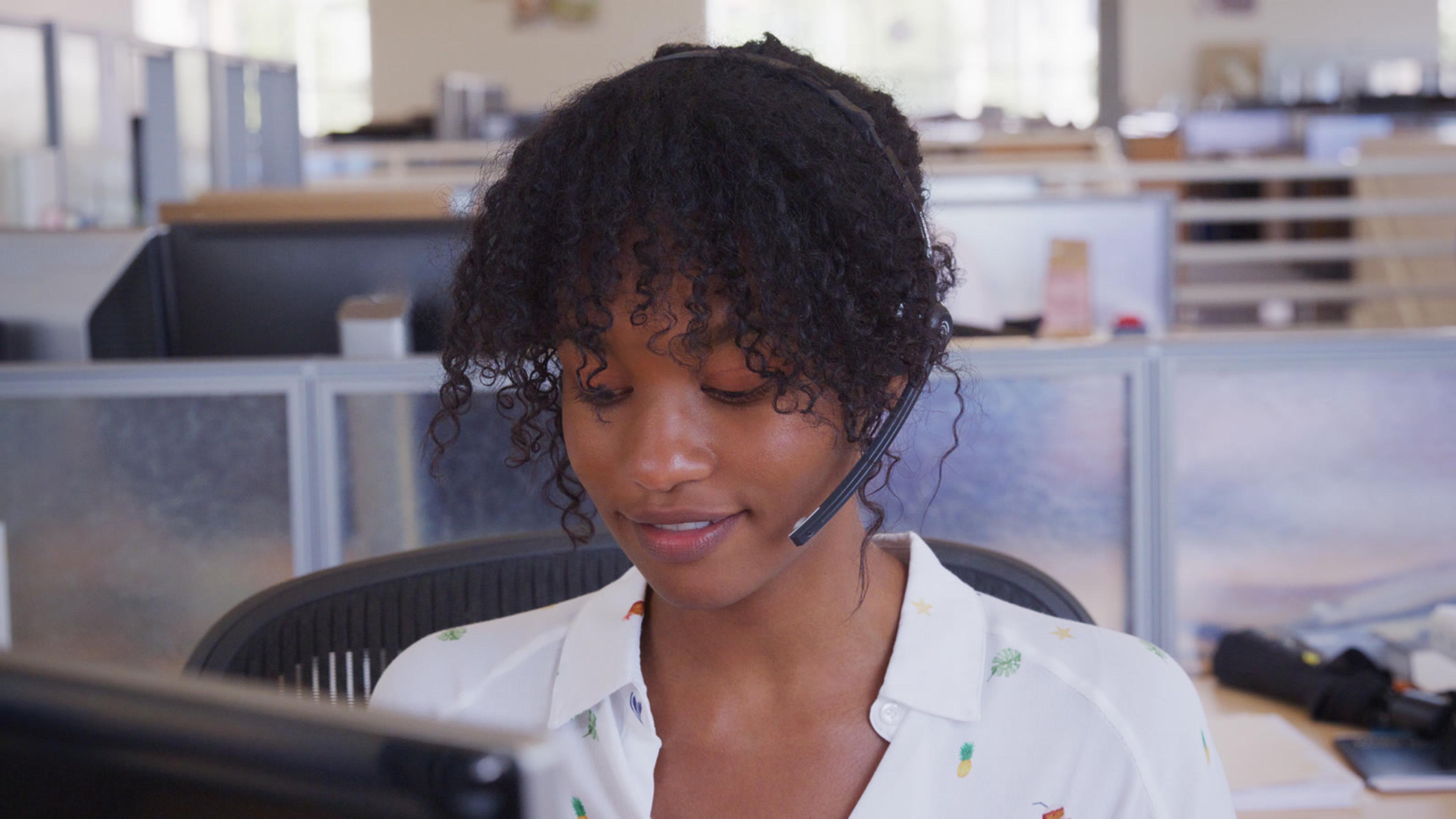 Professional woman with headset at a desk — hosting a three-way or SessionPBX conference call on softphone