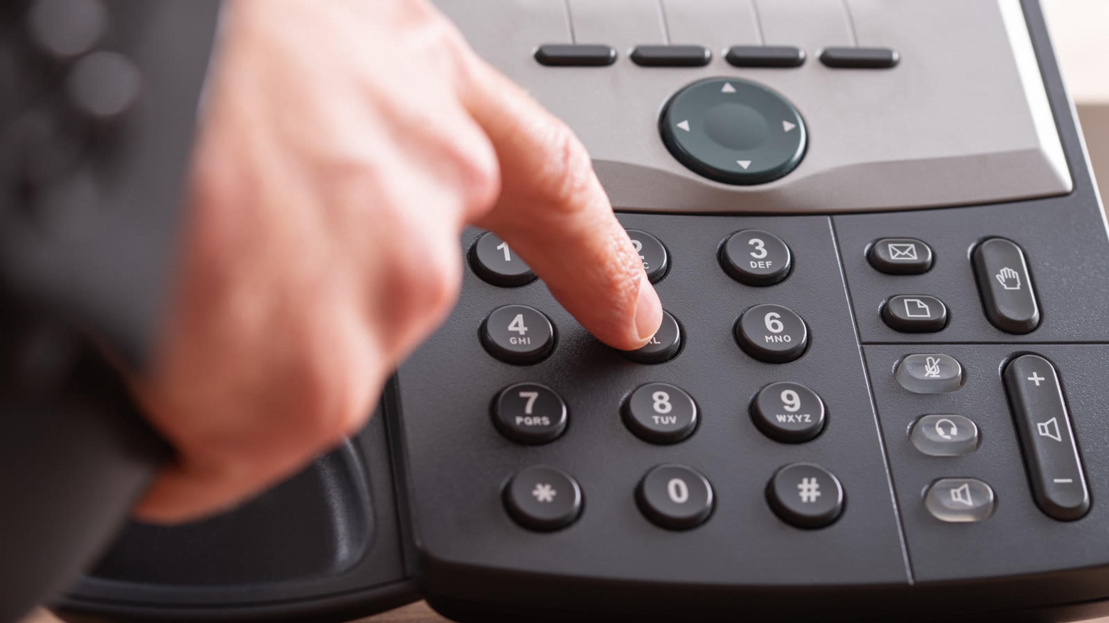 Hand dialing buttons on a modern IP desk phone — trial and day-one calling test