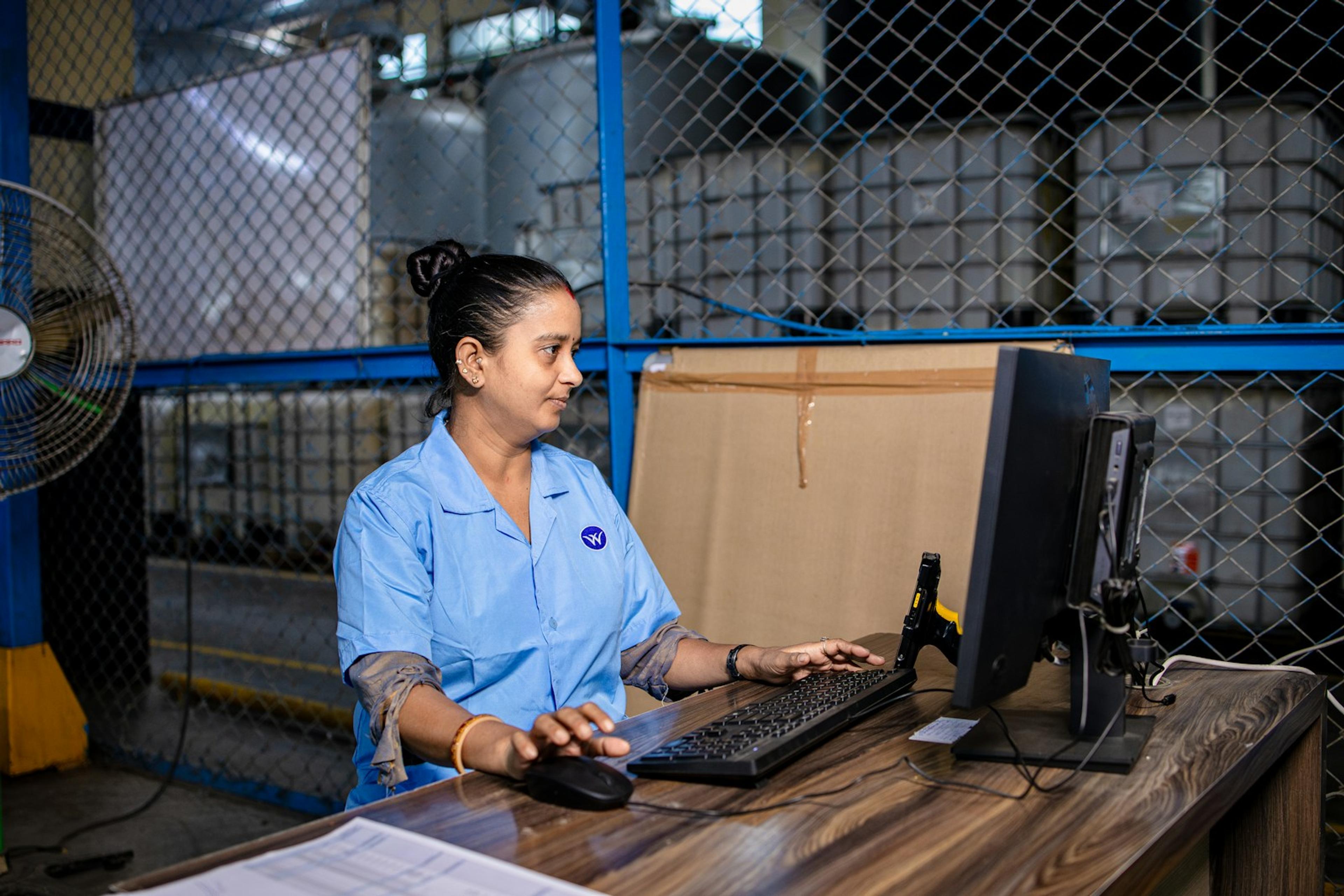 Warehouse operations employee using a computer beside ecommerce inventory
