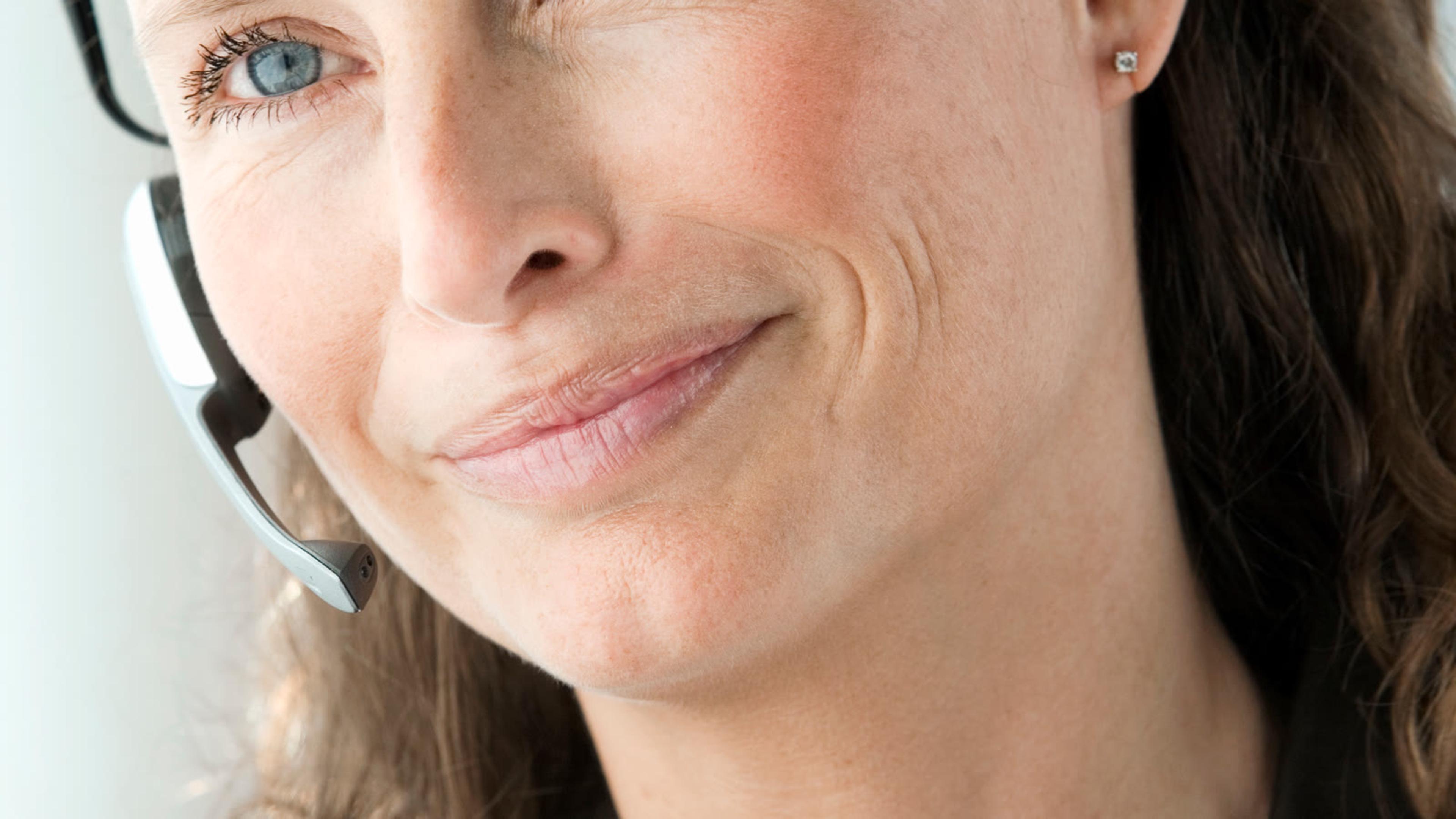 Business woman smiling with a headset indoors — softphone headset lifestyle for FreePBX mobile teams