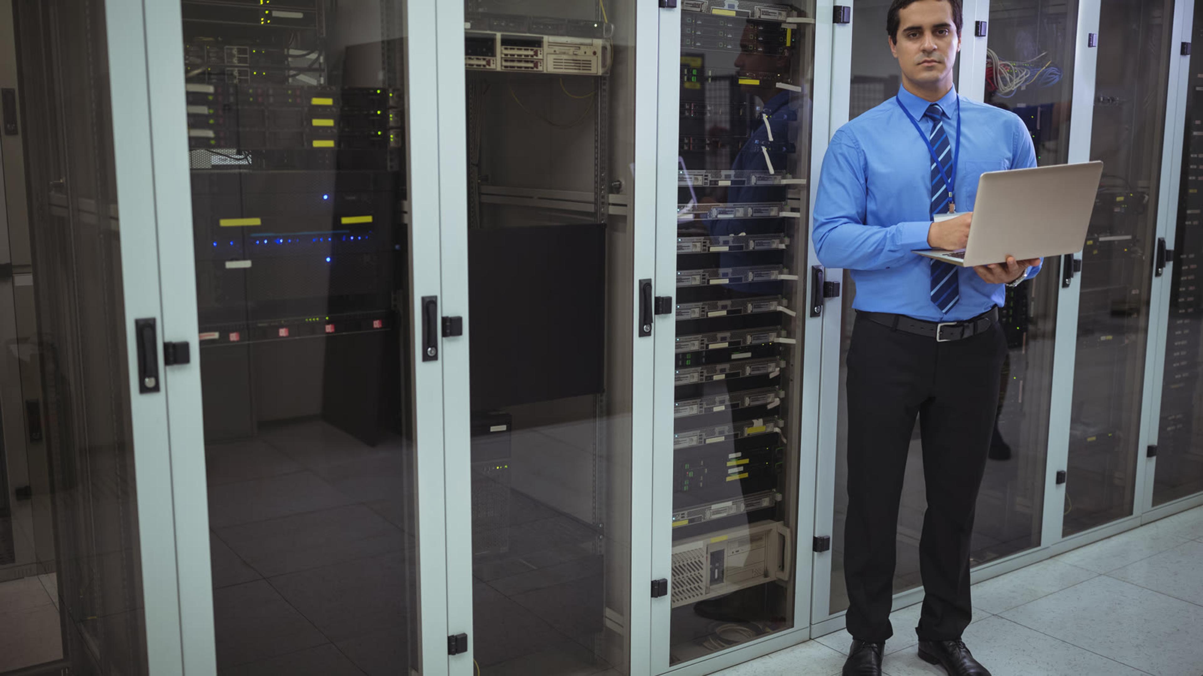 IT engineer holding a laptop in a data centre, where a partner could self-host the phone system for many customers