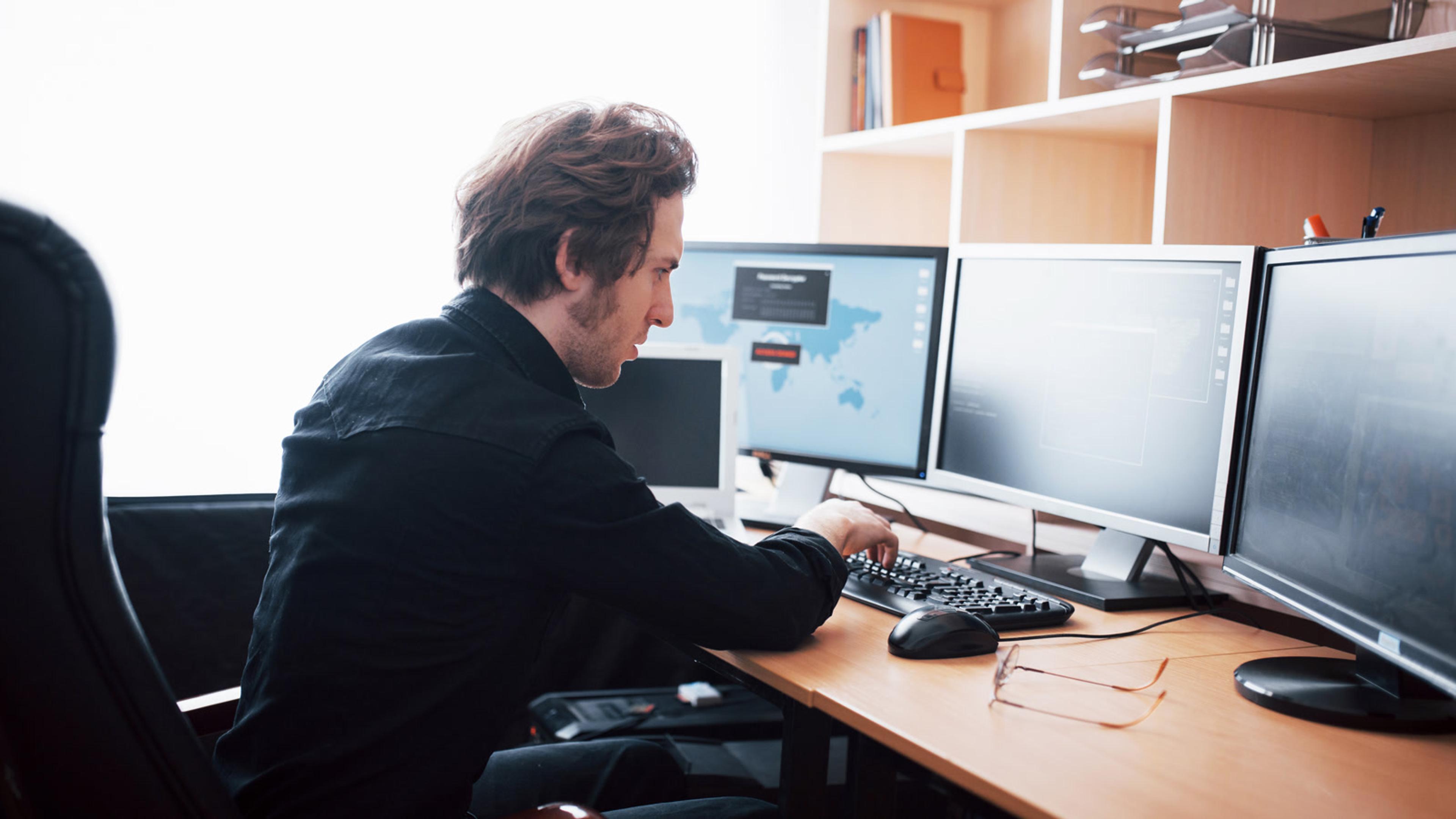 Man working at a computer in a bright office provisioning FusionPBX softphones