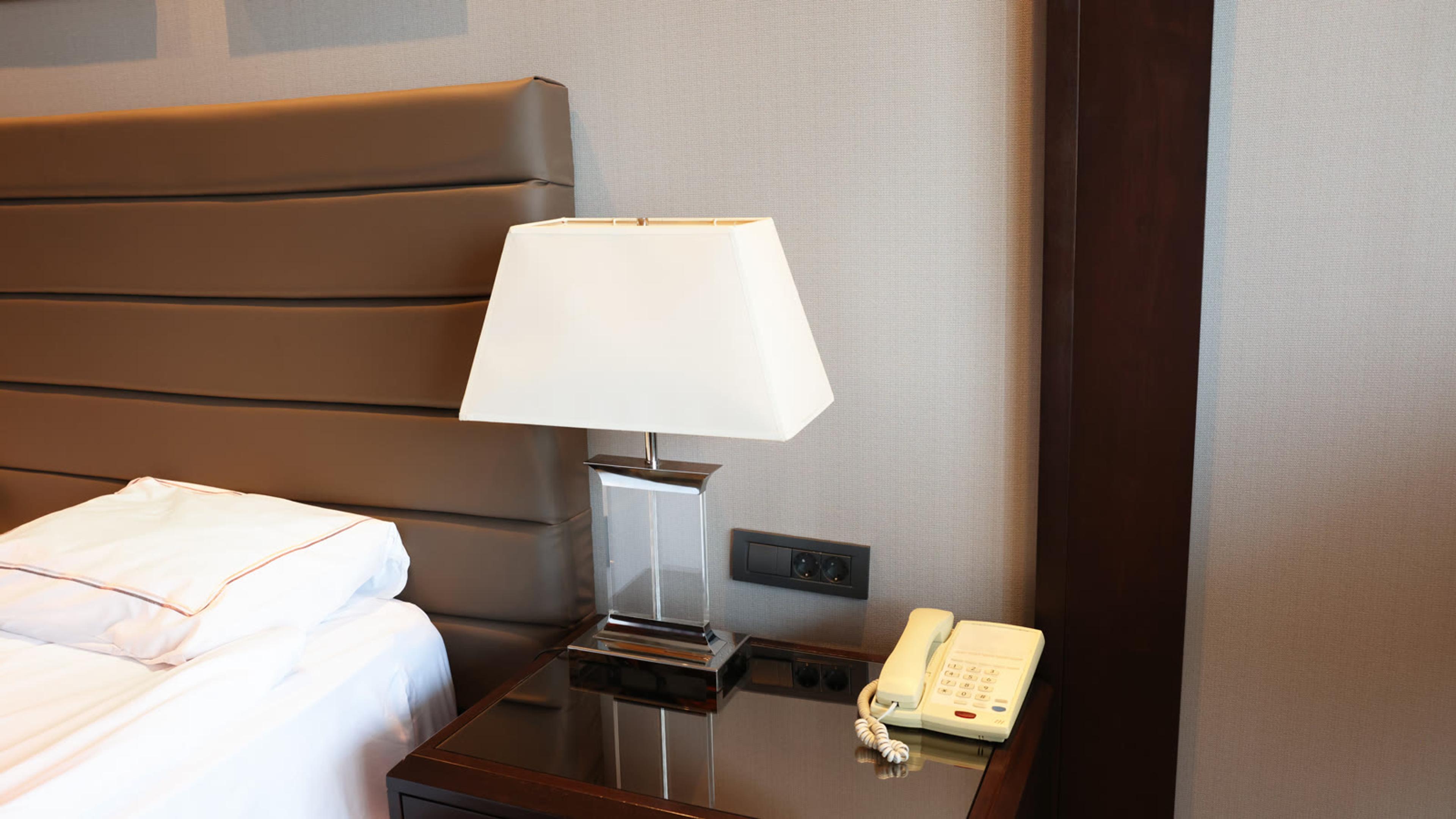Modern hotel bedside table with lamp and guest-room telephone