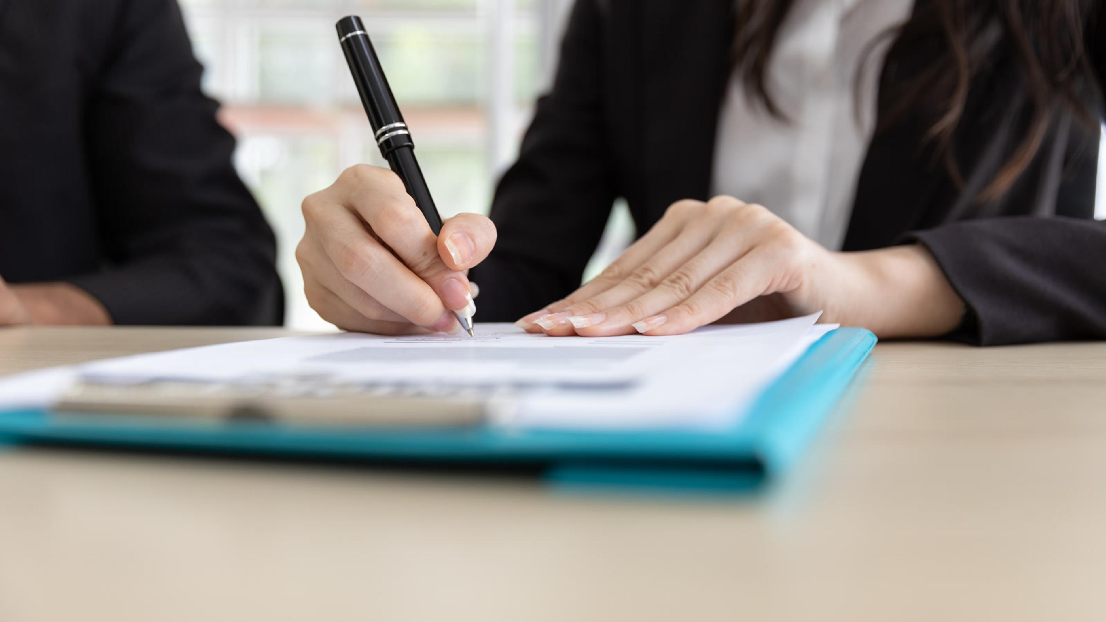 Businesswoman signing documents with a coworker — number porting paperwork