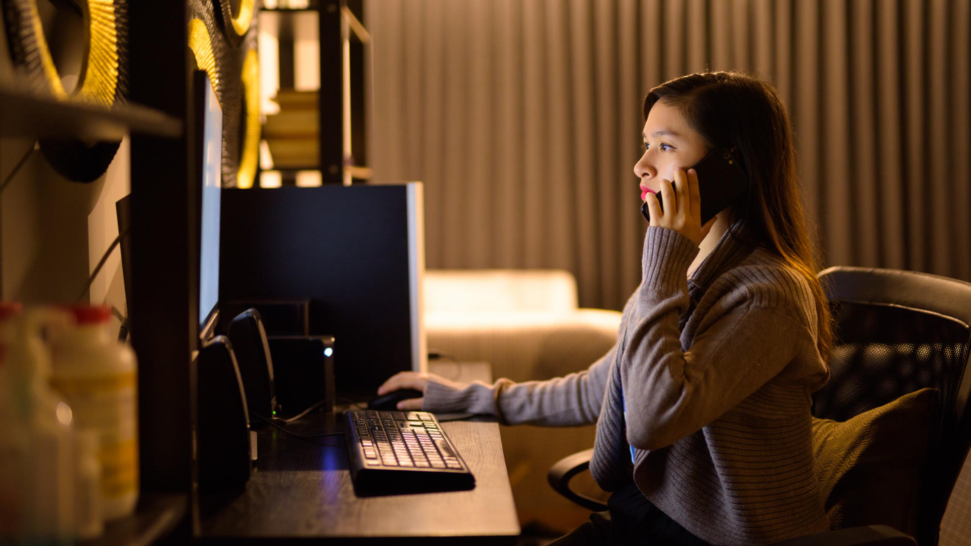 Woman working from home on a computer while taking an after-hours business call