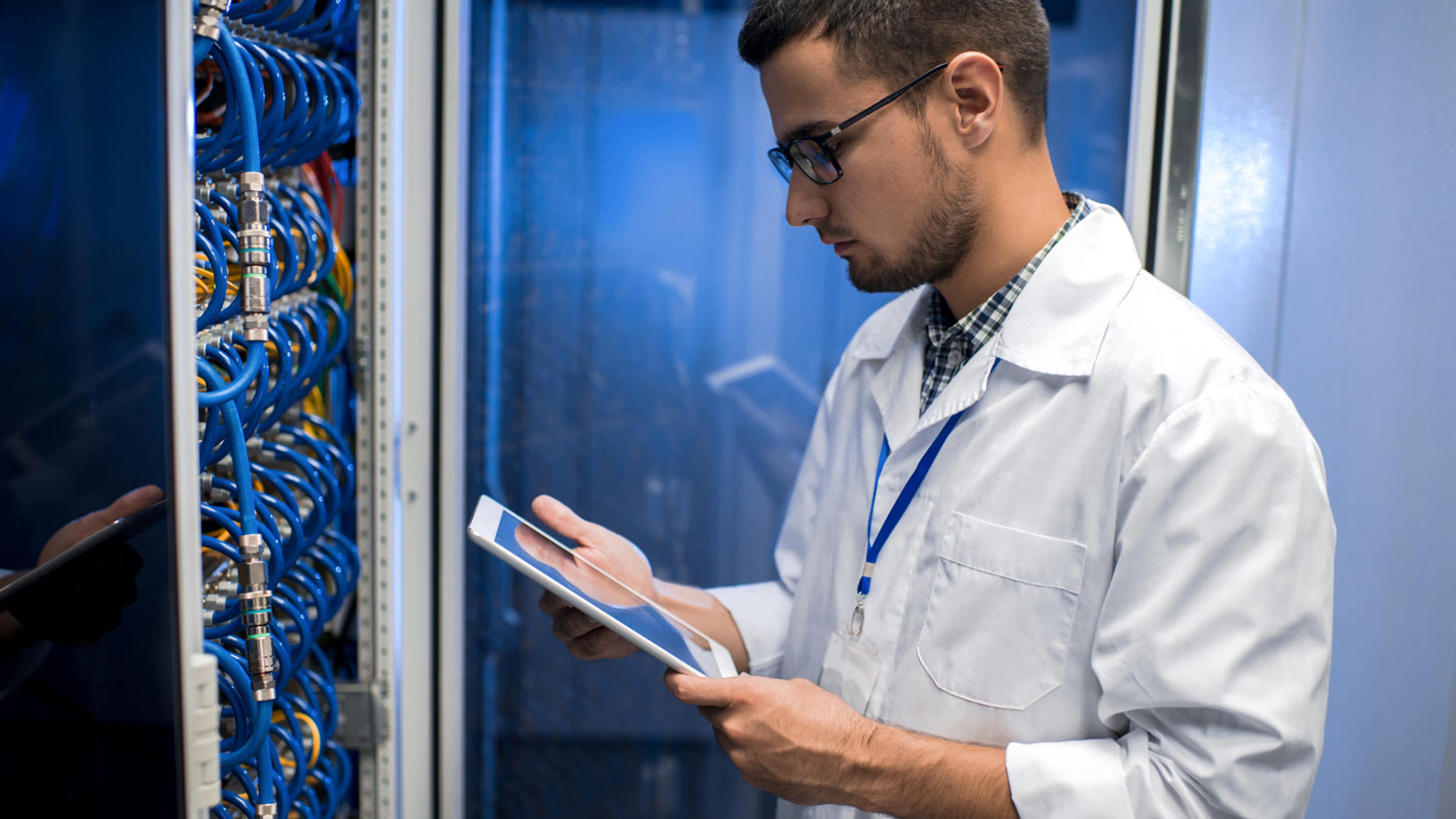 Network engineer checking a server rack on a tablet, where a partner could self-host the PBX