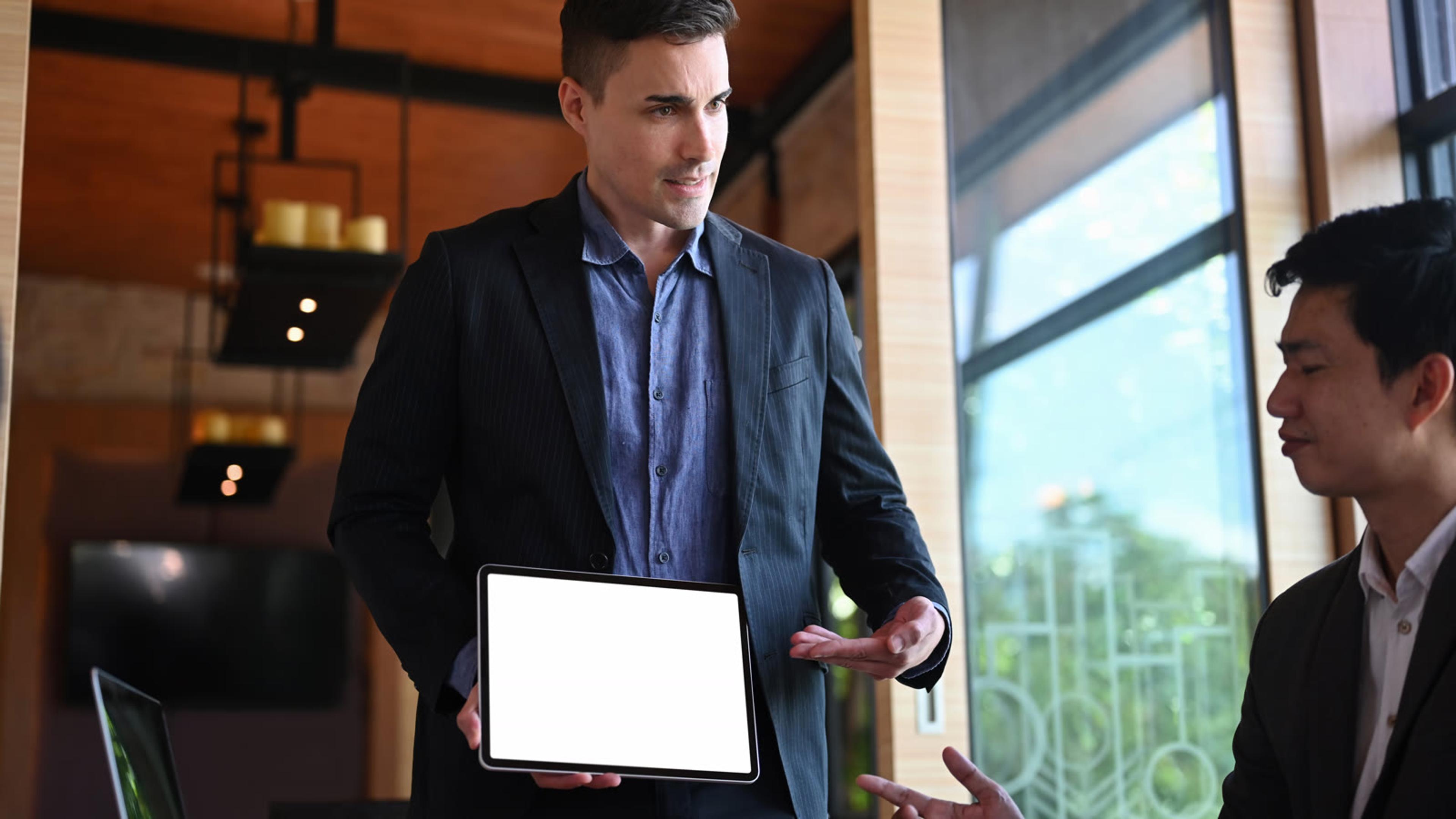Two MSP managers reviewing a hosted voice service plan on a tablet in an office