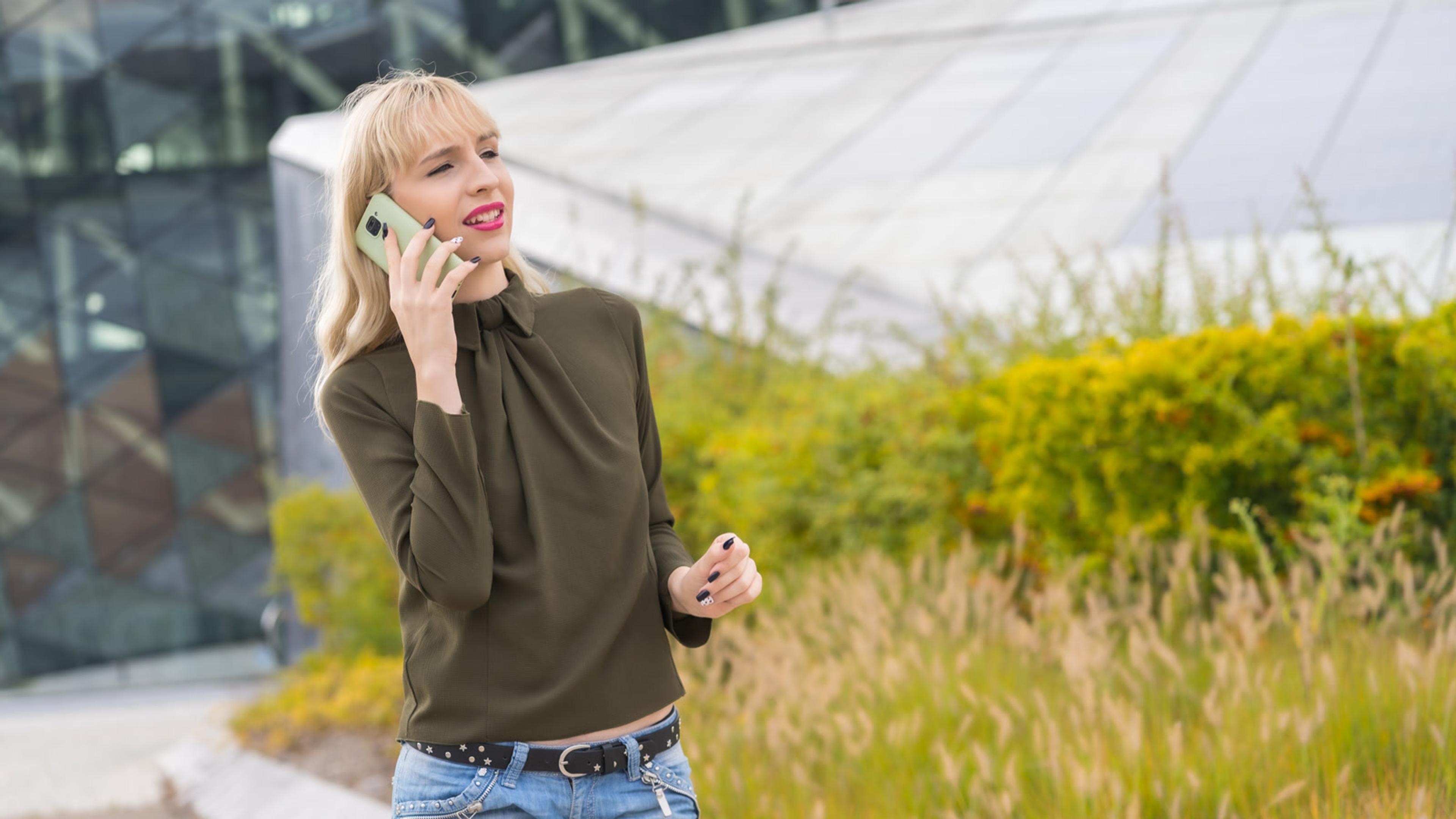 Woman talking on a cell phone in a city park — mobile softphone on the go