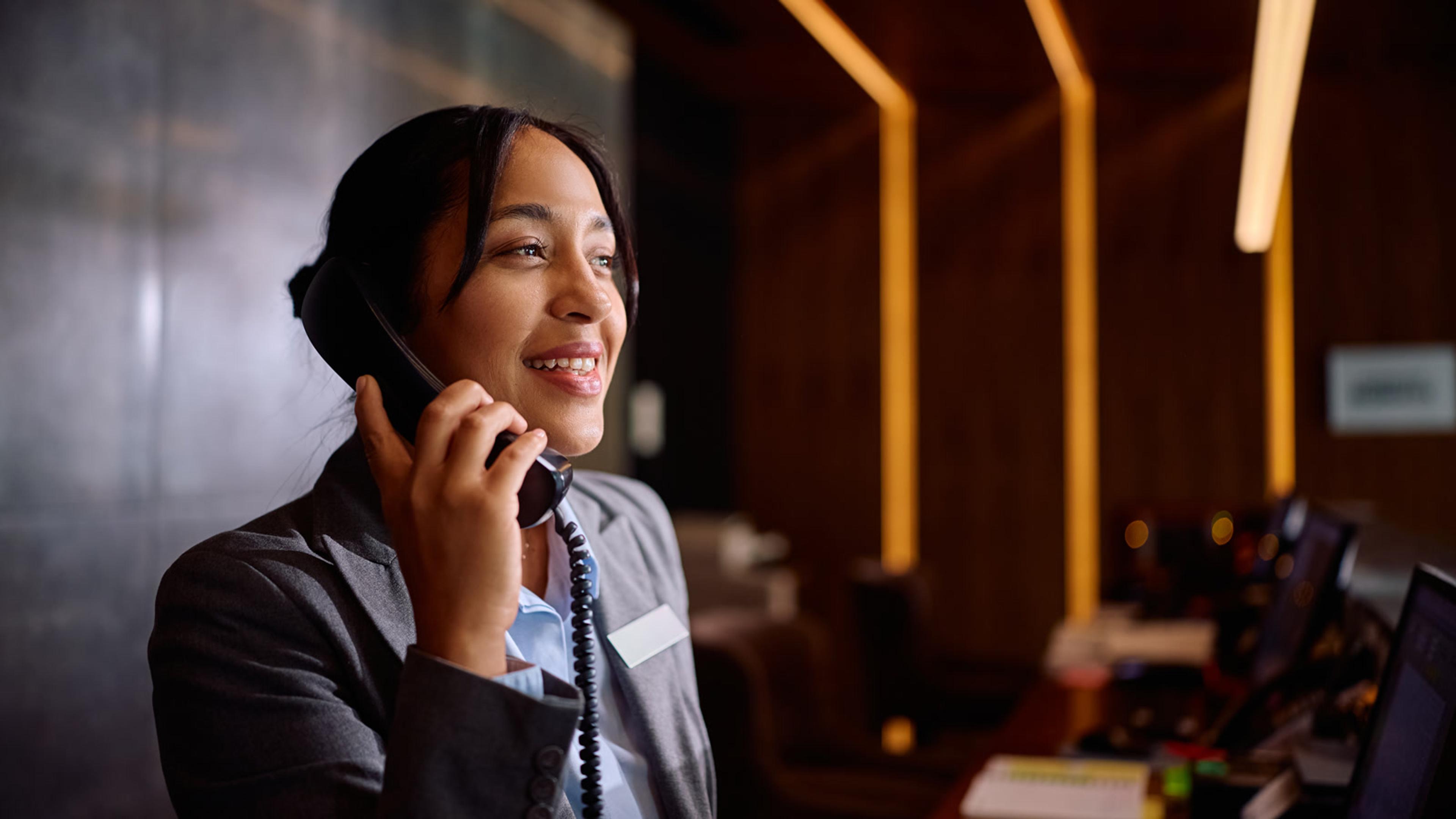 Professional receptionist smiling while talking on the phone after auto-attendant routing
