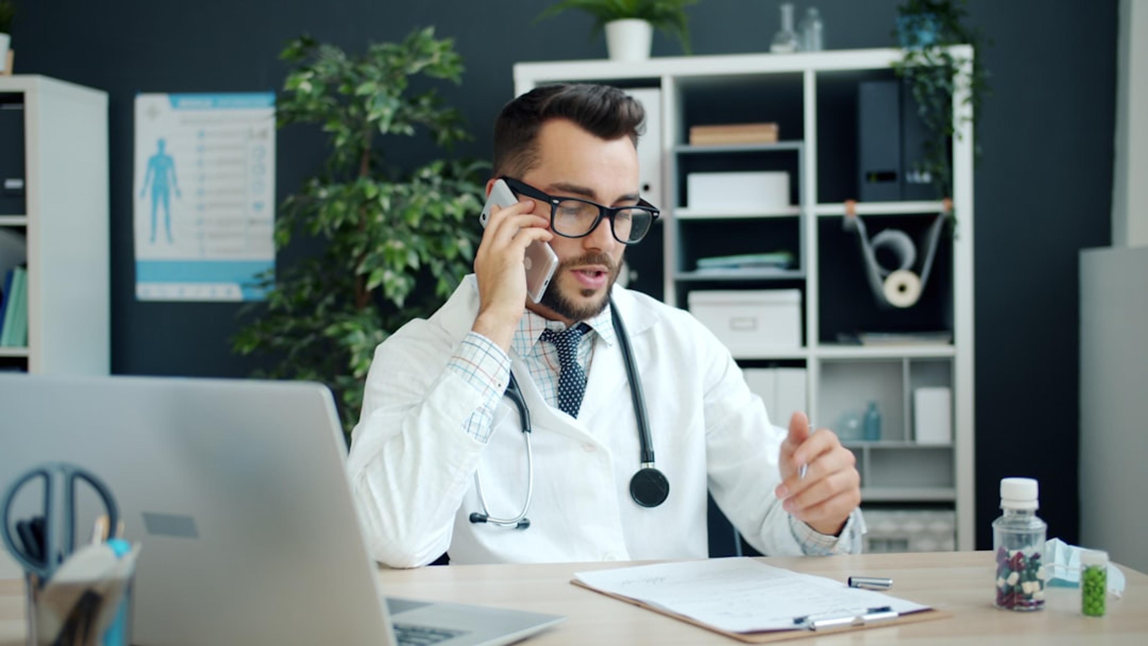 Doctor speaking on a mobile phone while working in a clinic office