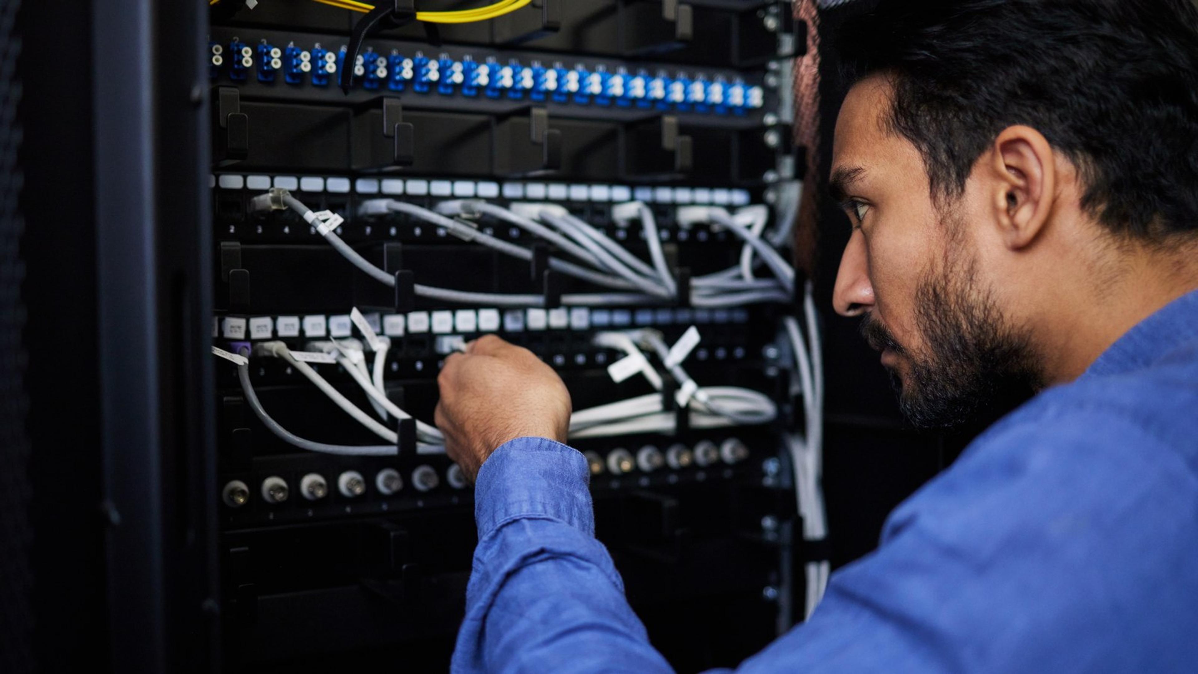 Technician working on patch-panel cables in a server rack during maintenance