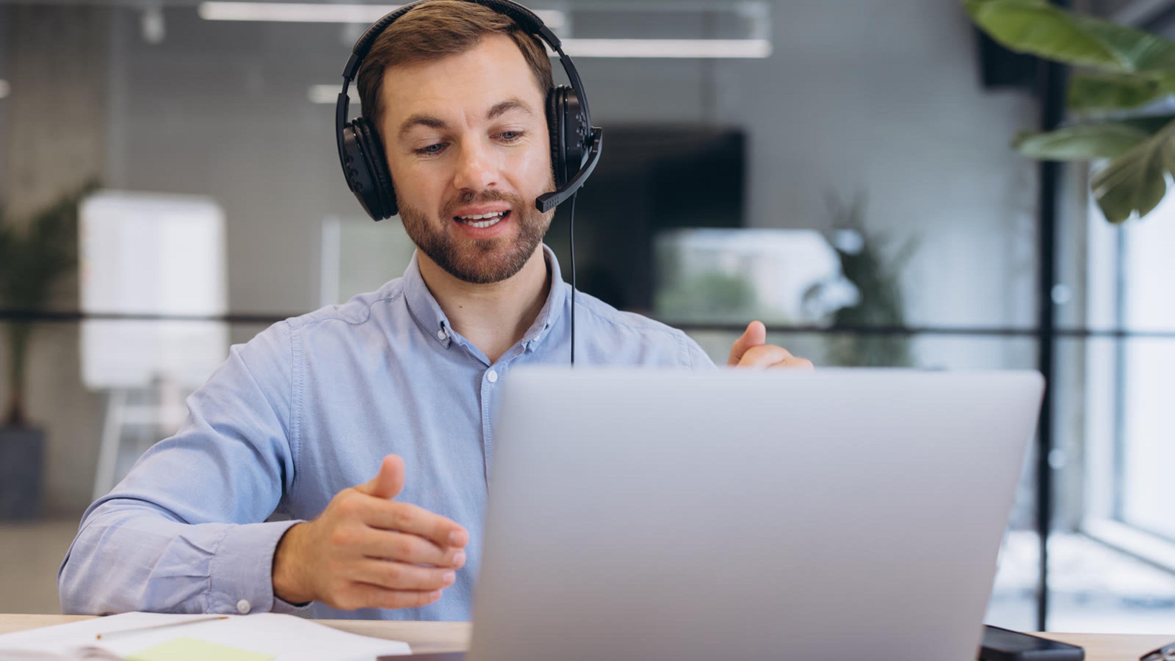 IT professional wearing a headset on a video call at a laptop