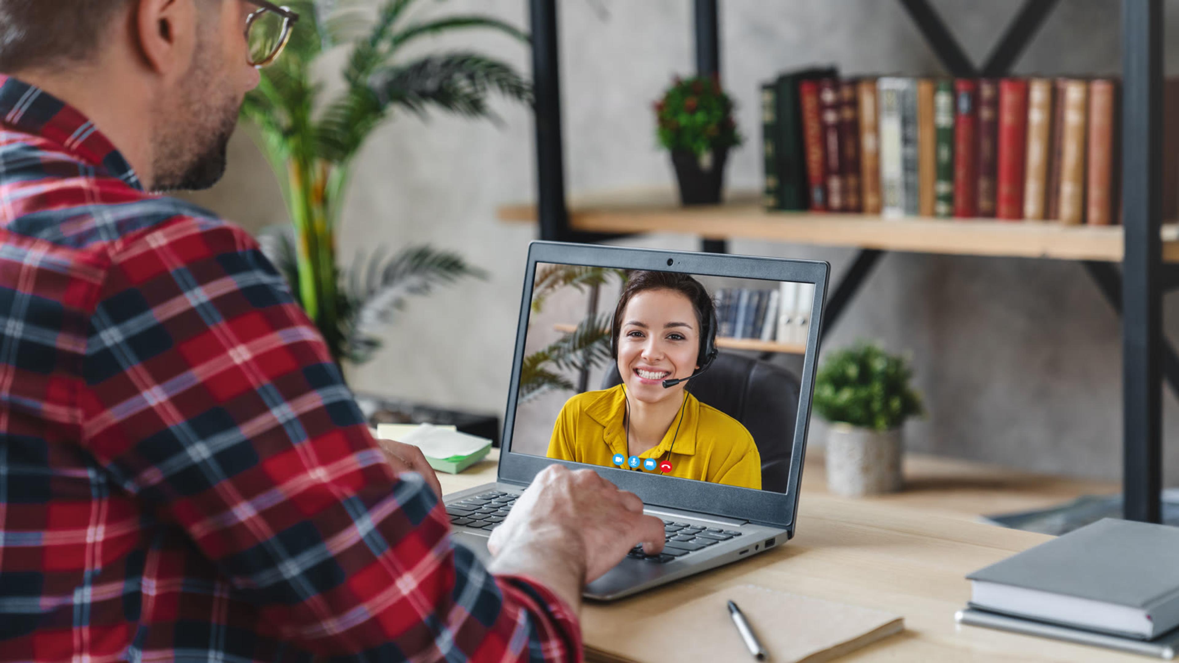 Man at an office desk on a video call with a colleague wearing a headset