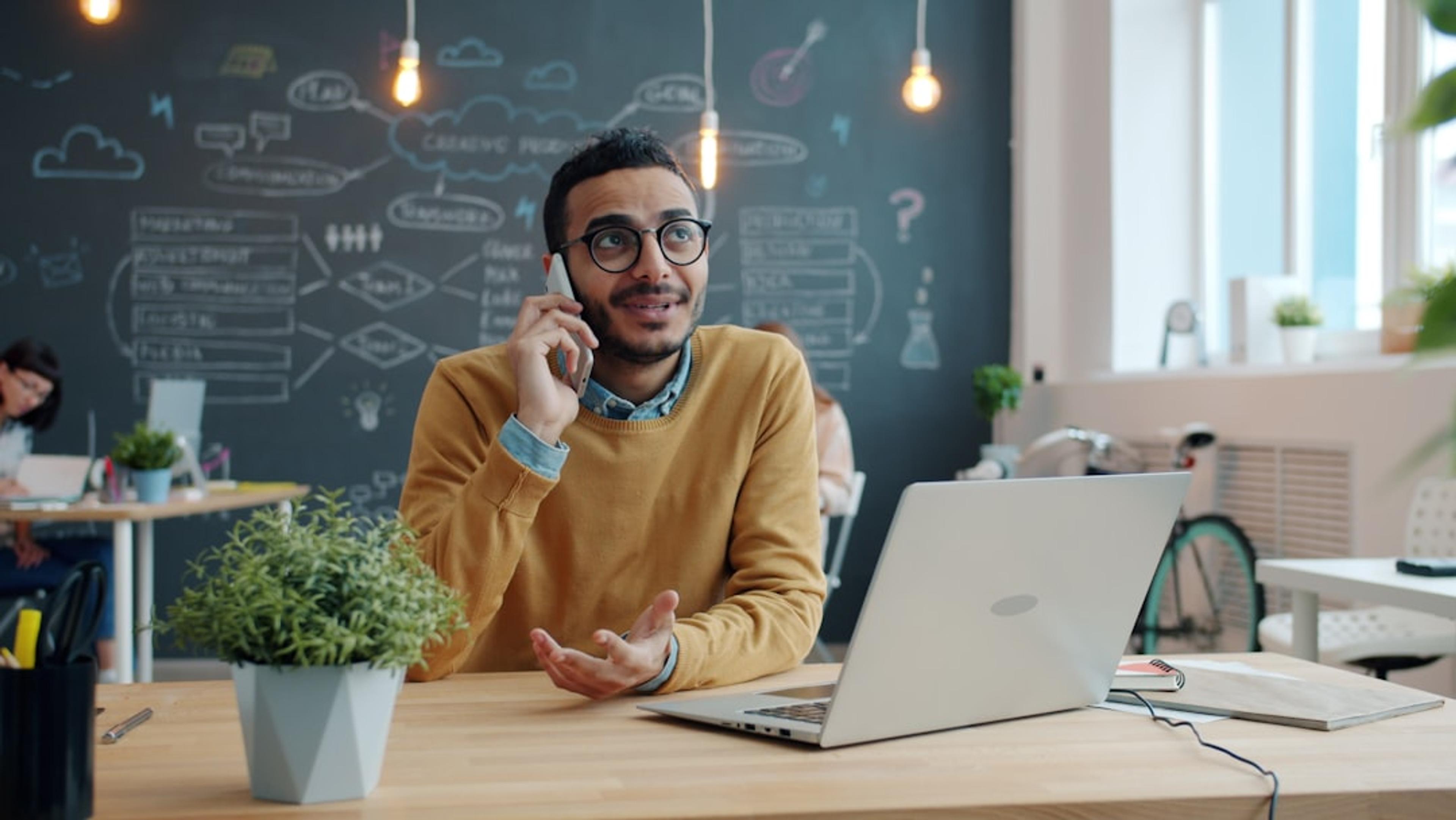 Business professional using a smartphone for work calls in a shared office