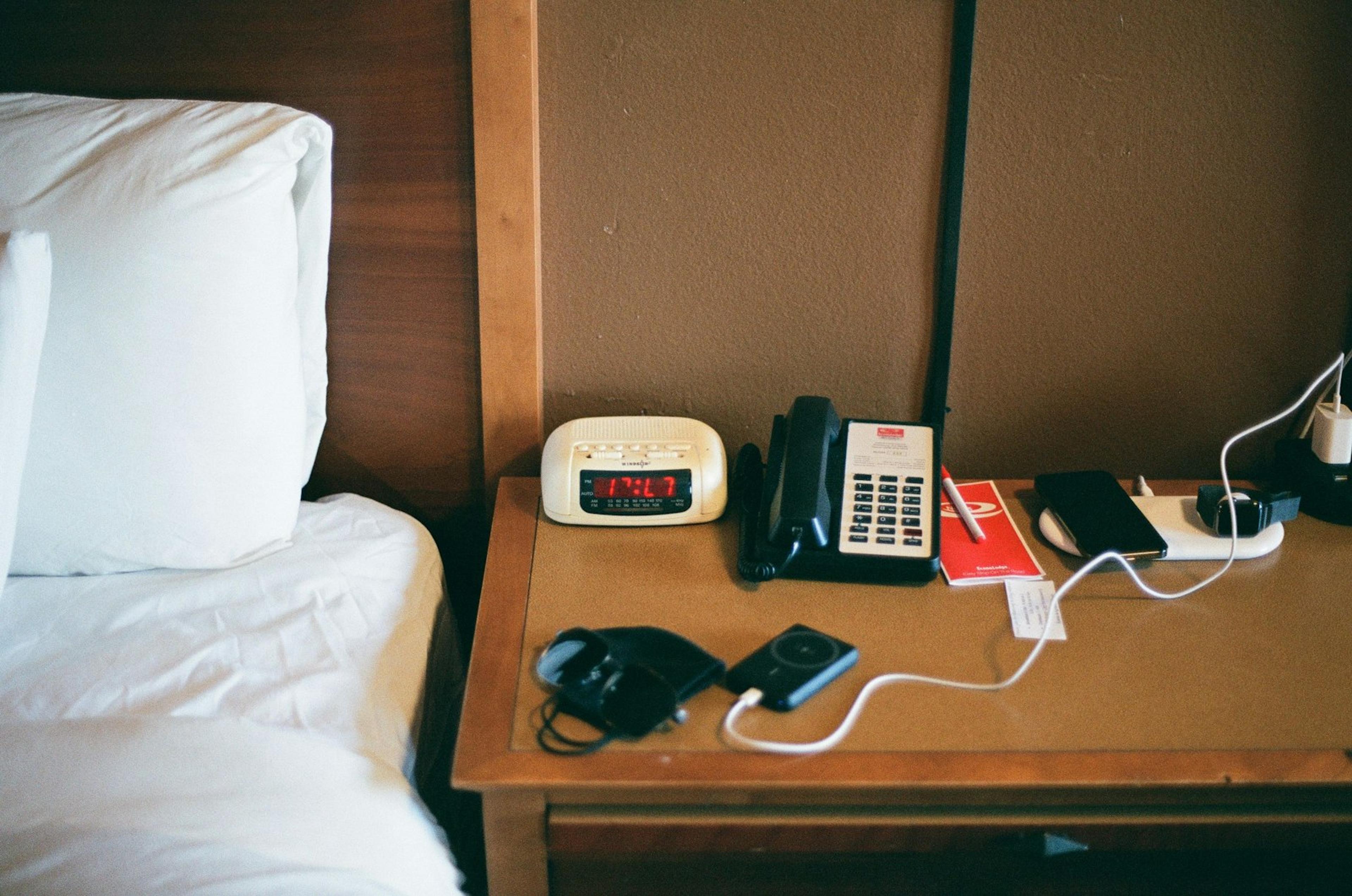 Telephone beside a hotel bed representing guest-room phone requirements
