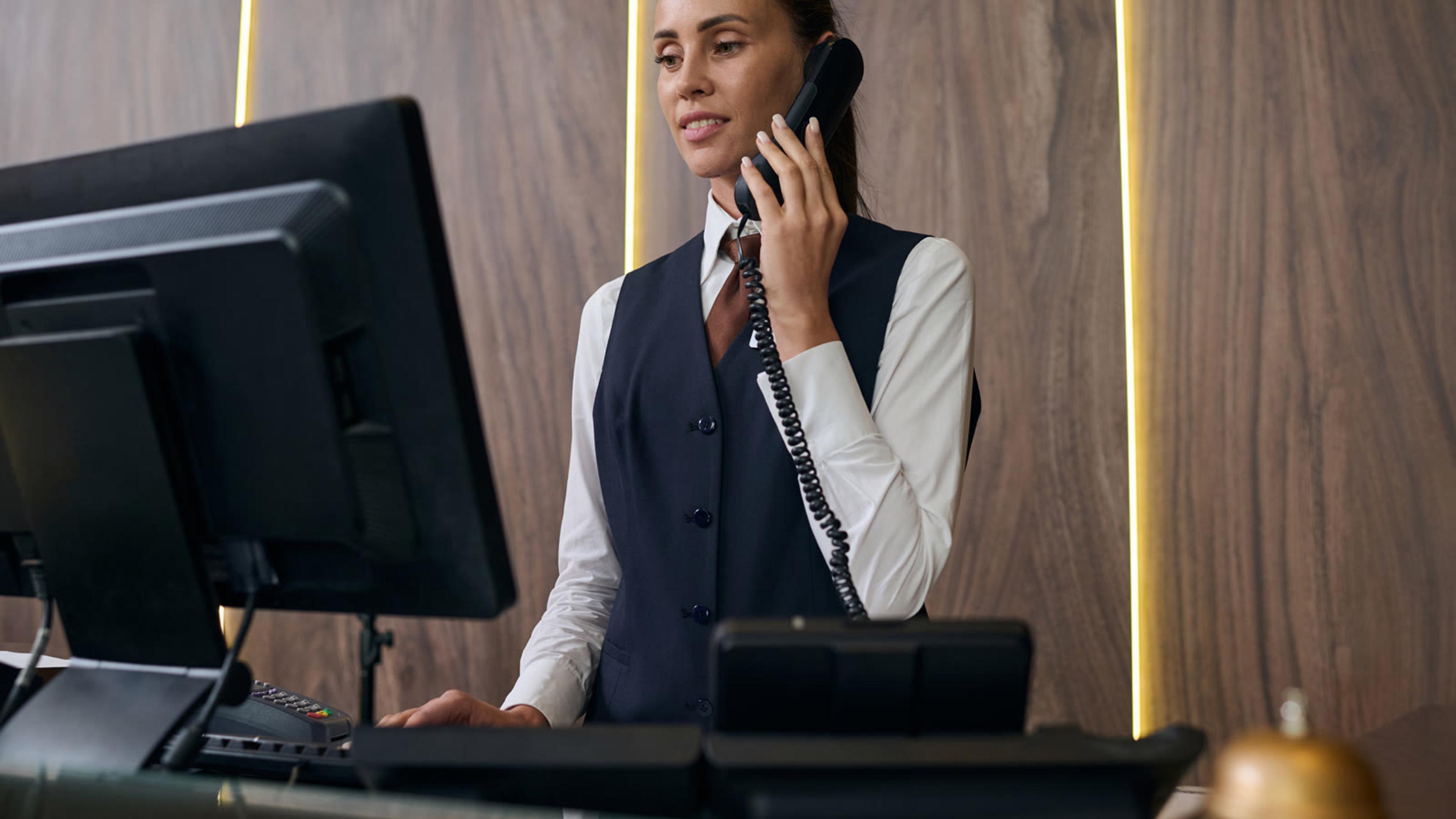 Hotel receptionist answering the phone at the front desk