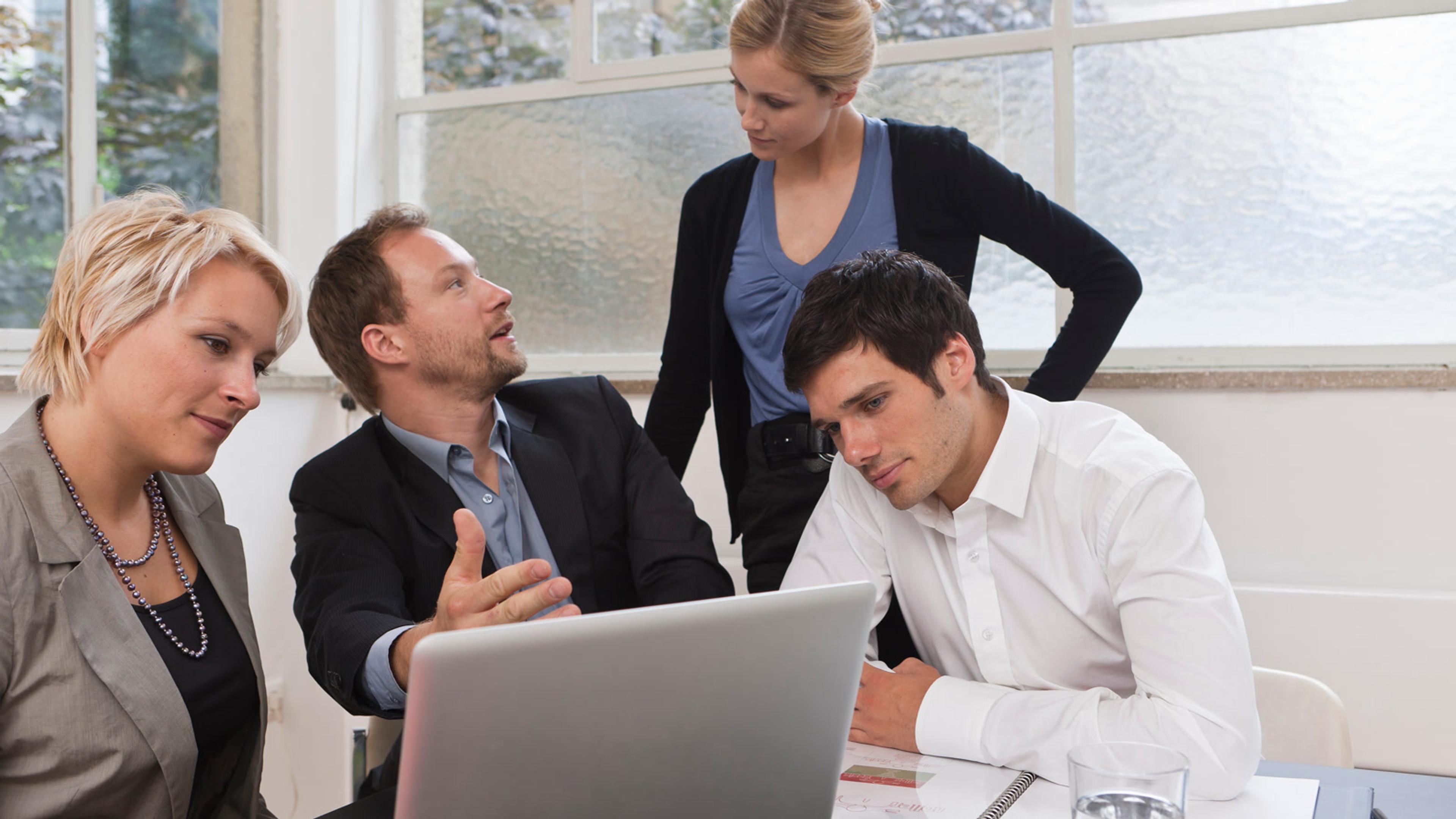 Professionals collaborating around a laptop — phishing awareness training and report-phish coaching
