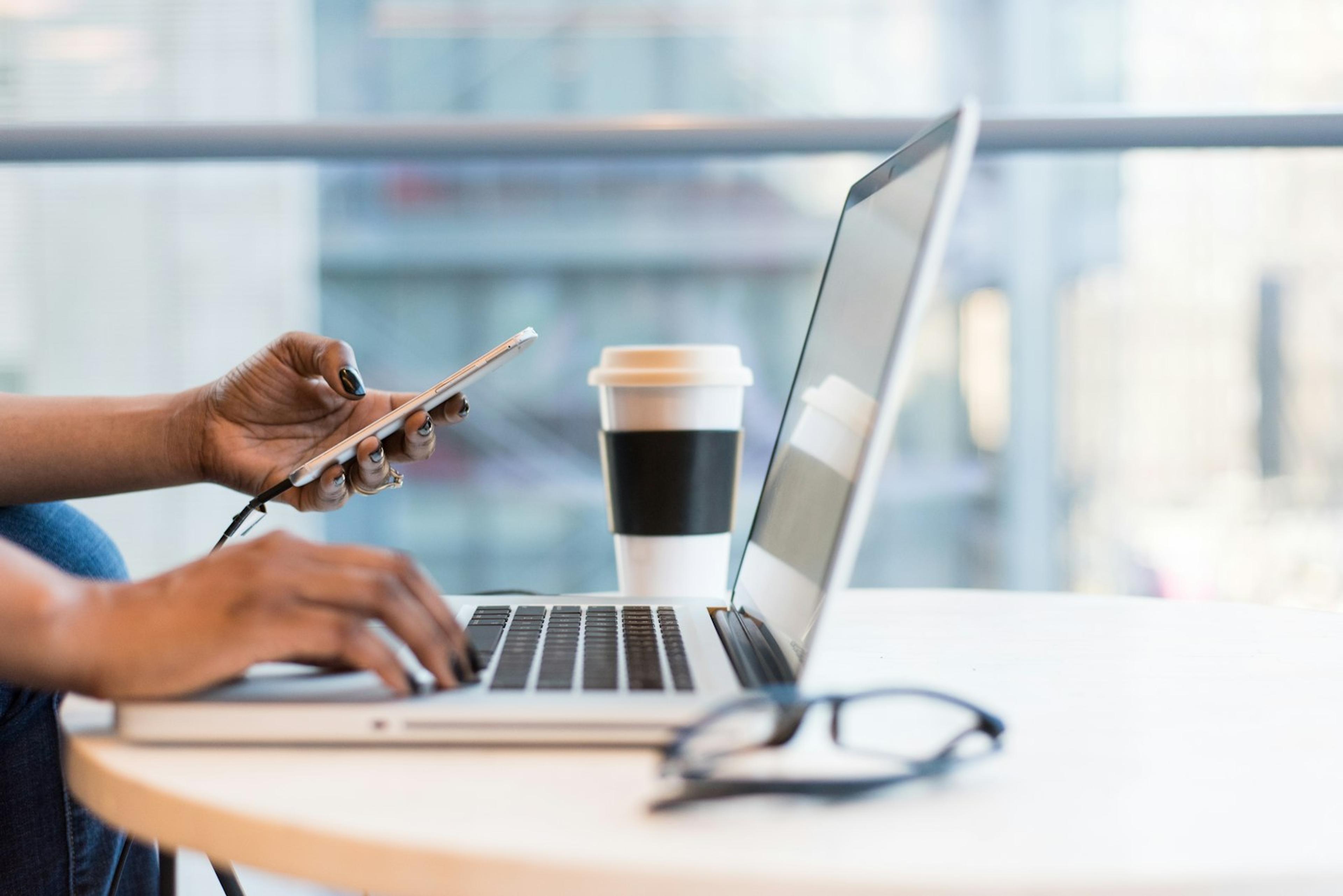 Business user testing a mobile phone beside a laptop in an office