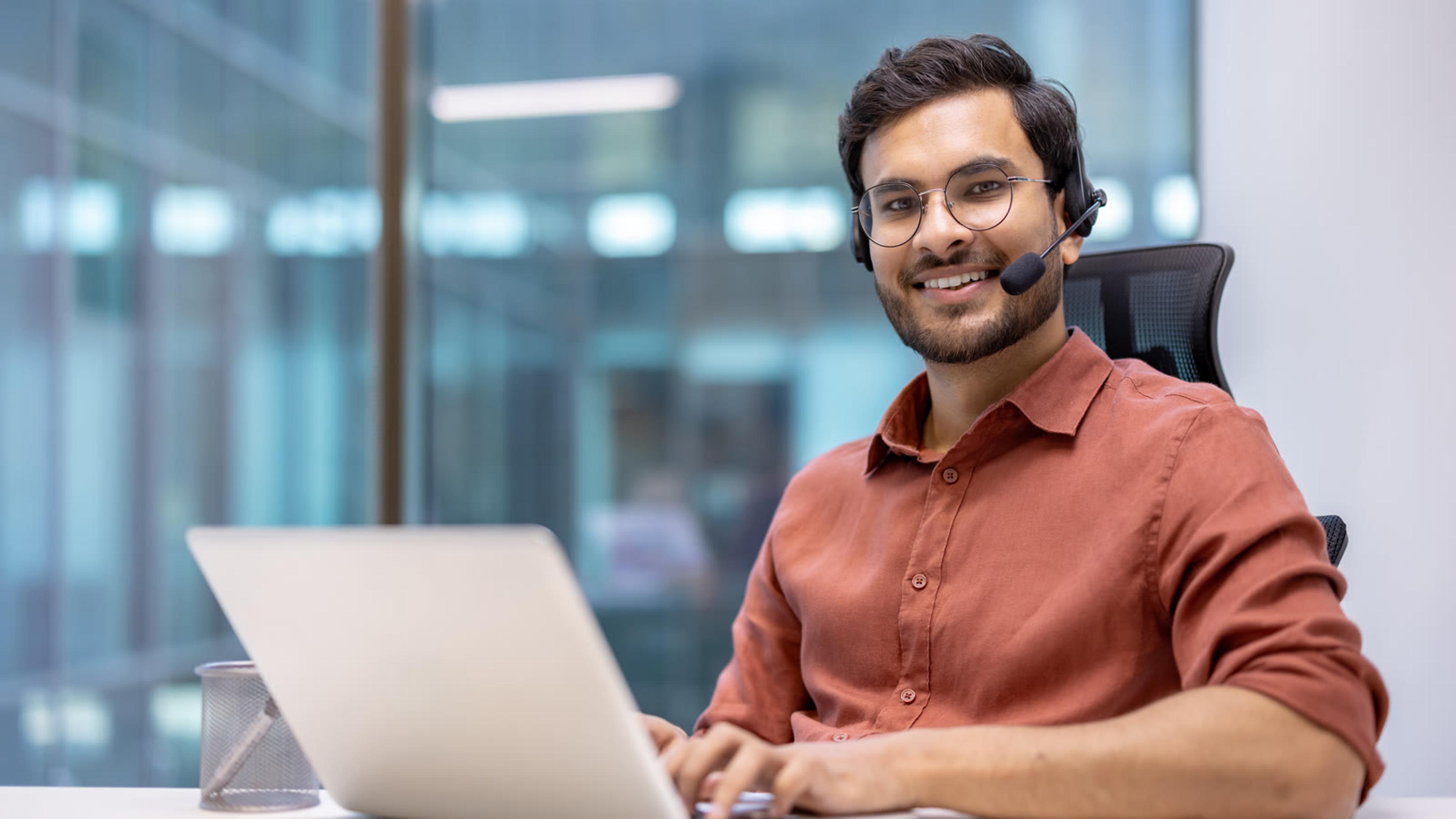 Professional wearing a headset at a desk with laptop — softphone and hybrid seat setup