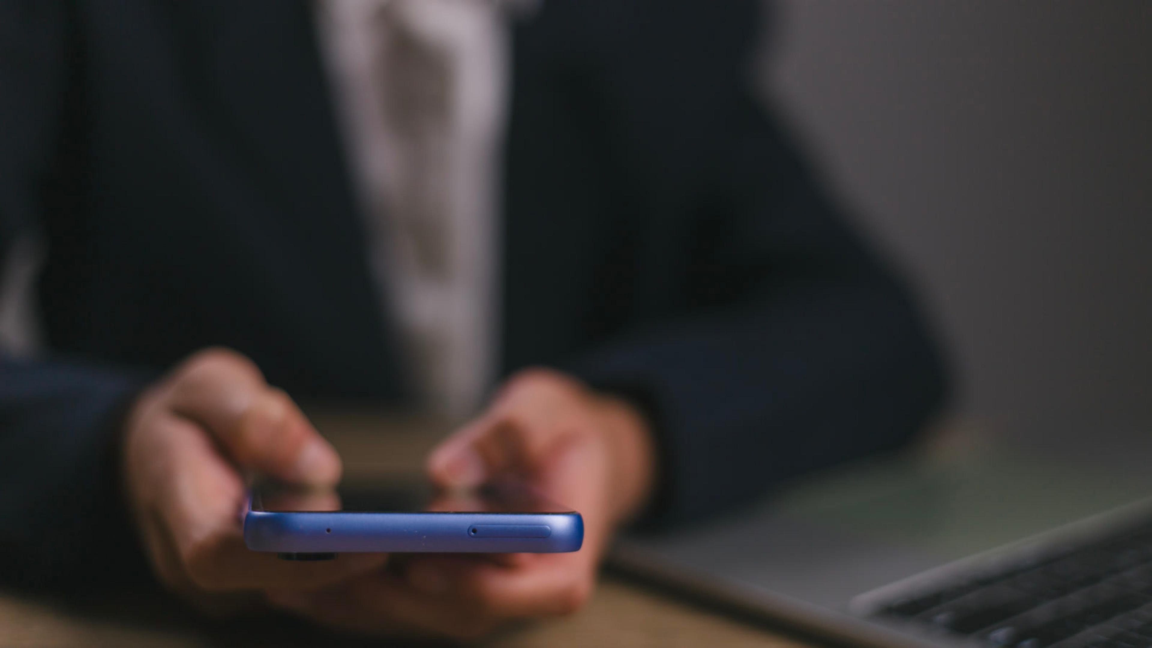 Professional using a phone near a laptop at the workplace — mobile softphone test