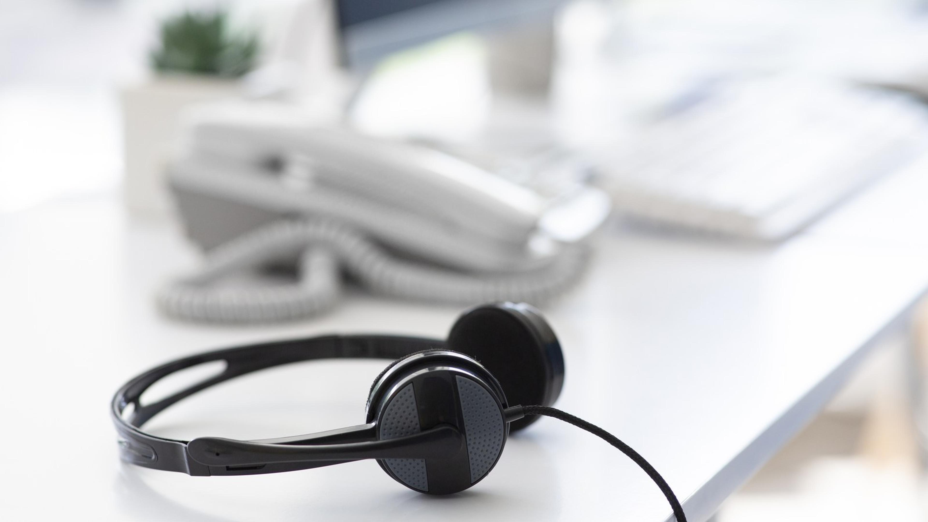 Headset and telephone on an office desk — desk VoIP and softphone hardware lifestyle