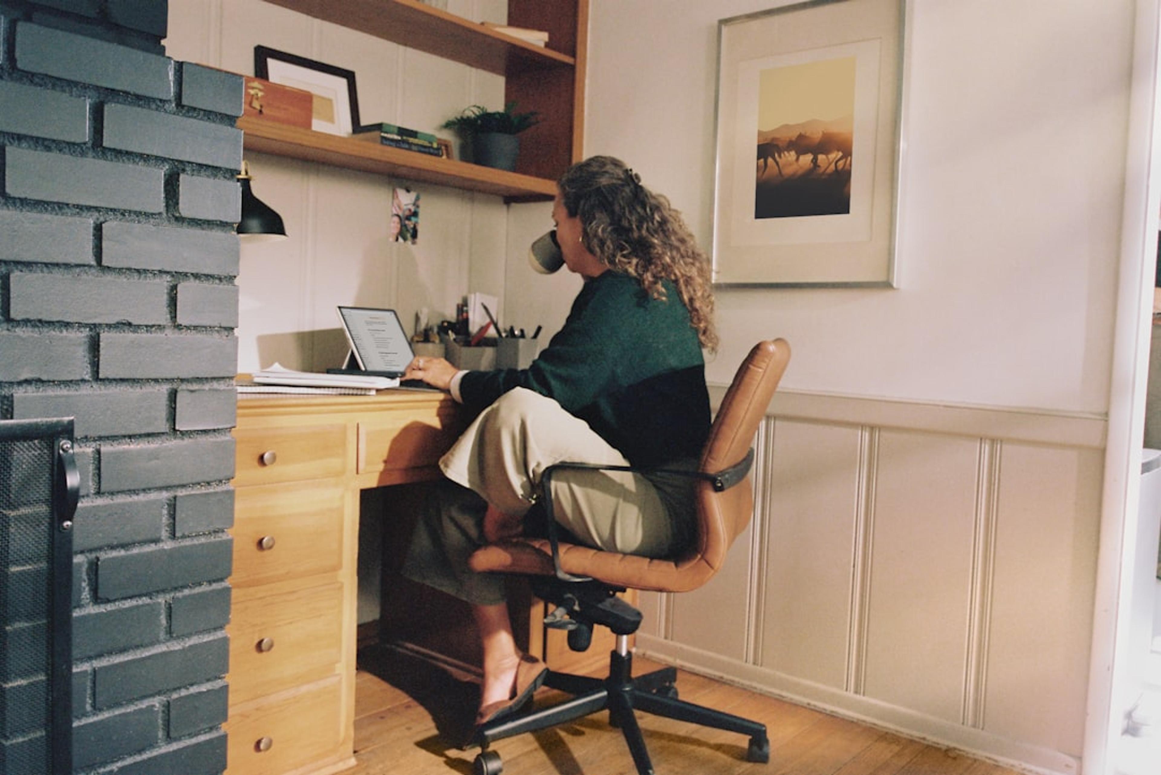 Remote professional working at a home-office desk with a laptop and phone