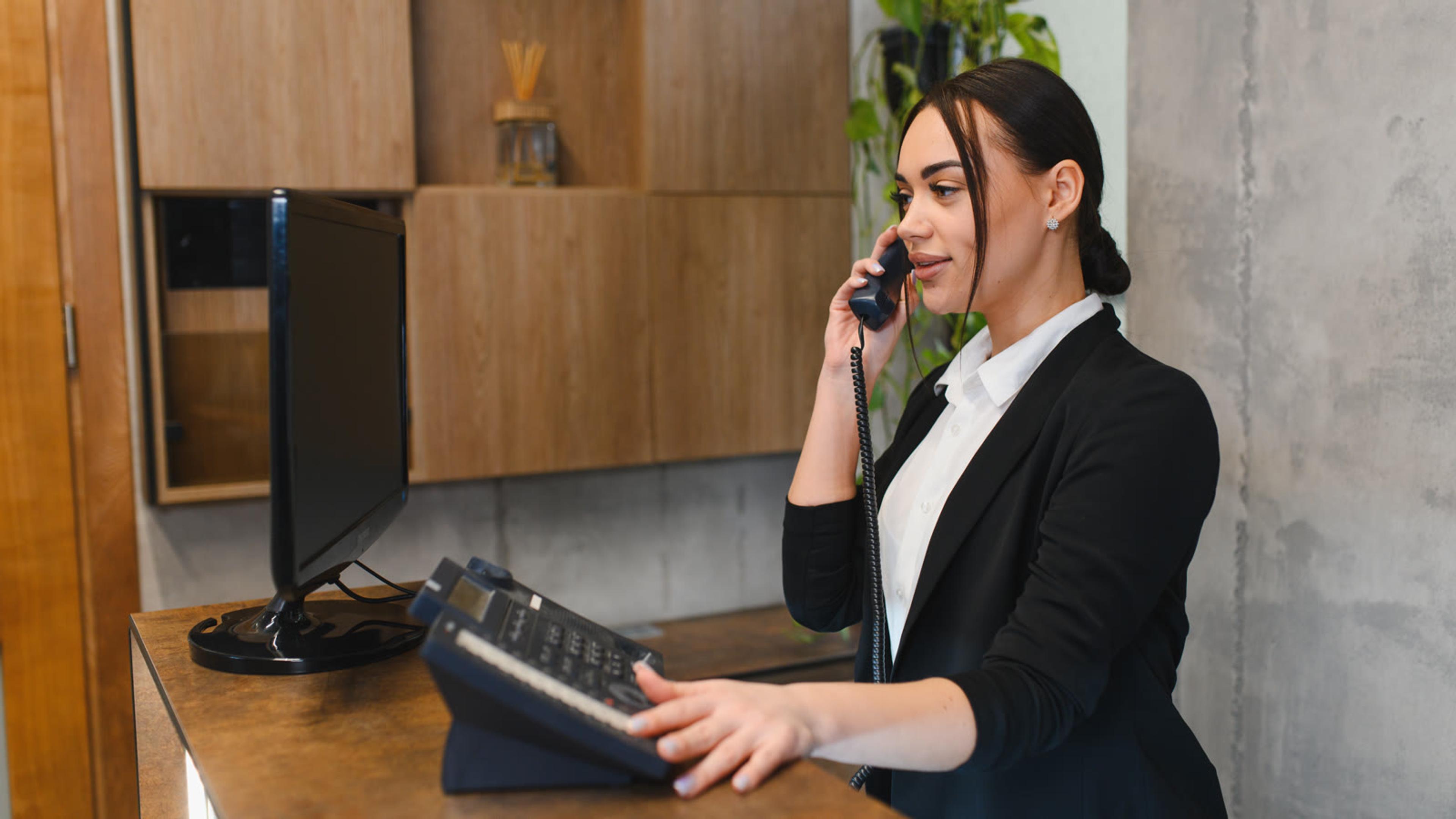 Professional young woman talking on phone at office — softphone on mobile