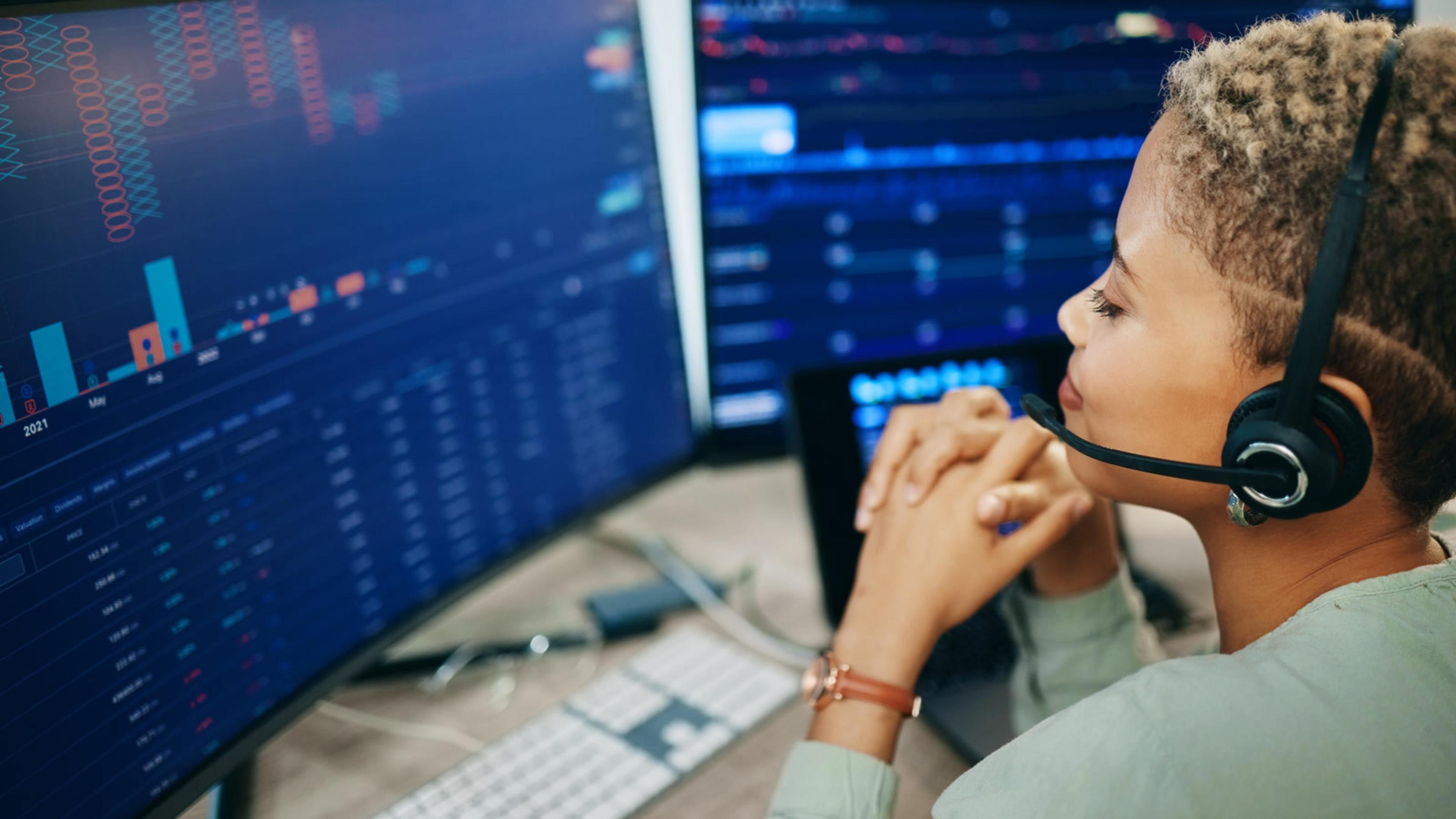 Woman working on a computer with a headset for contact-center customer routing