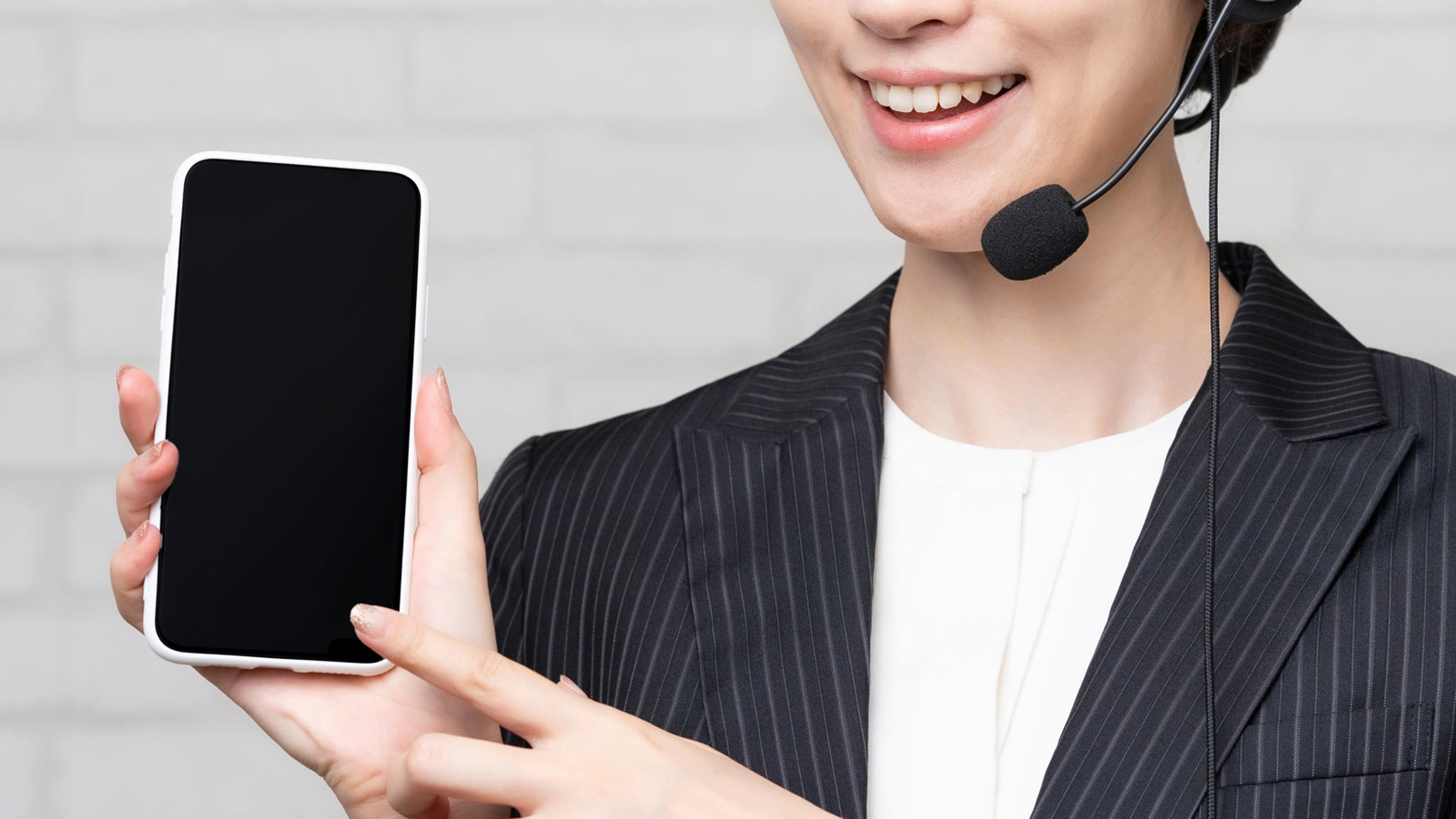 Woman showing a smartphone screen while wearing a headset — Android phone softphone in the office