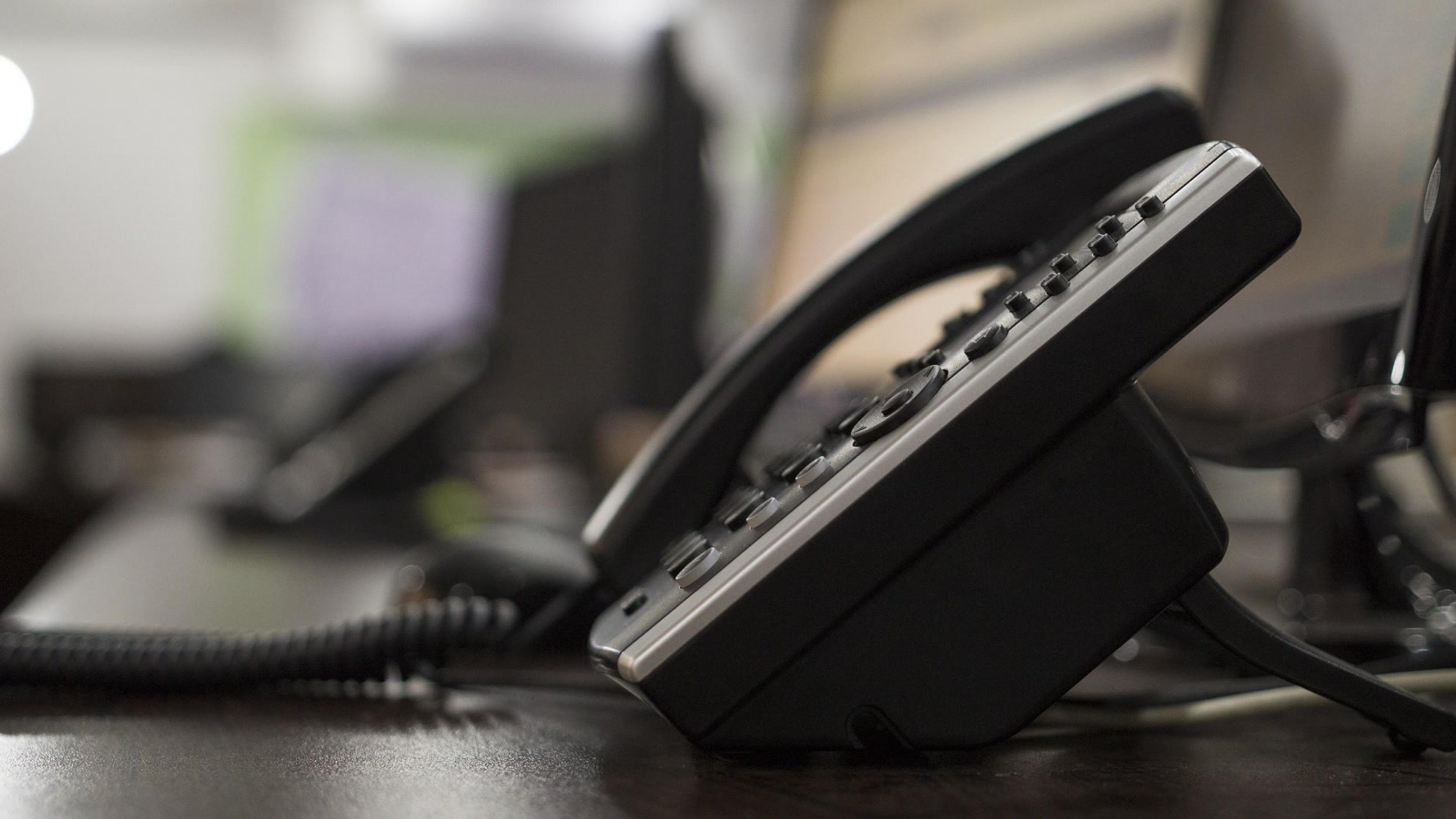 Modern office desk phone on dark wood — SessionPBX hosted PBX endpoint in a ring or hunt group
