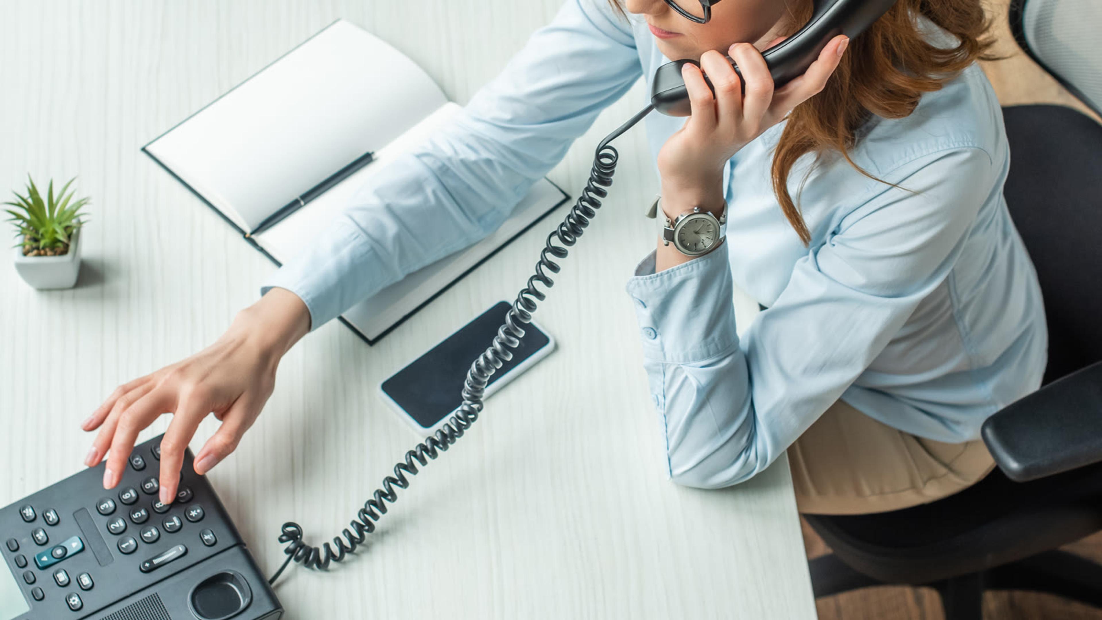 Woman answering a desk phone in a bright modern office