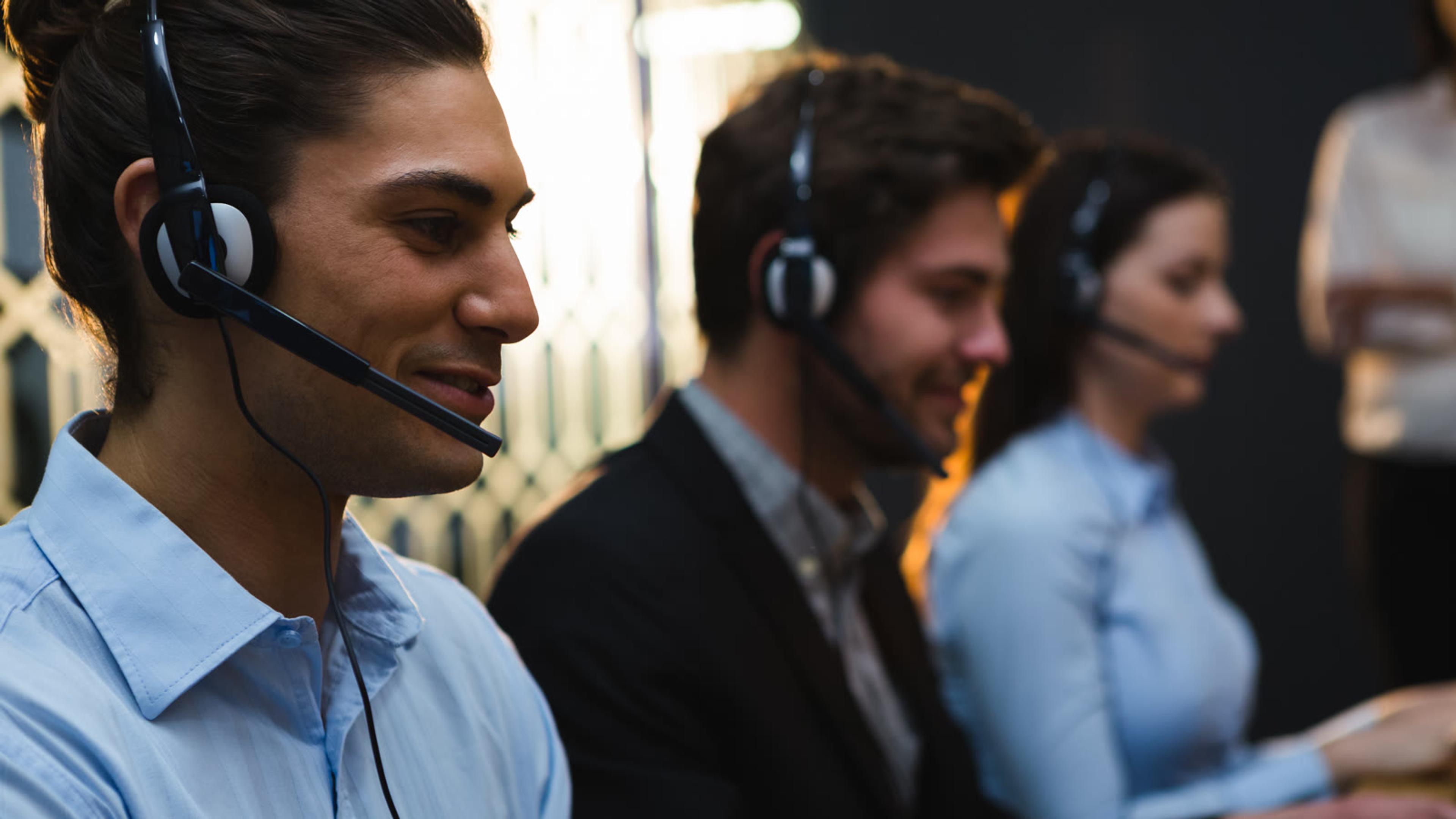 Call center staff at desks with headsets — softphone call transfer and conference controls