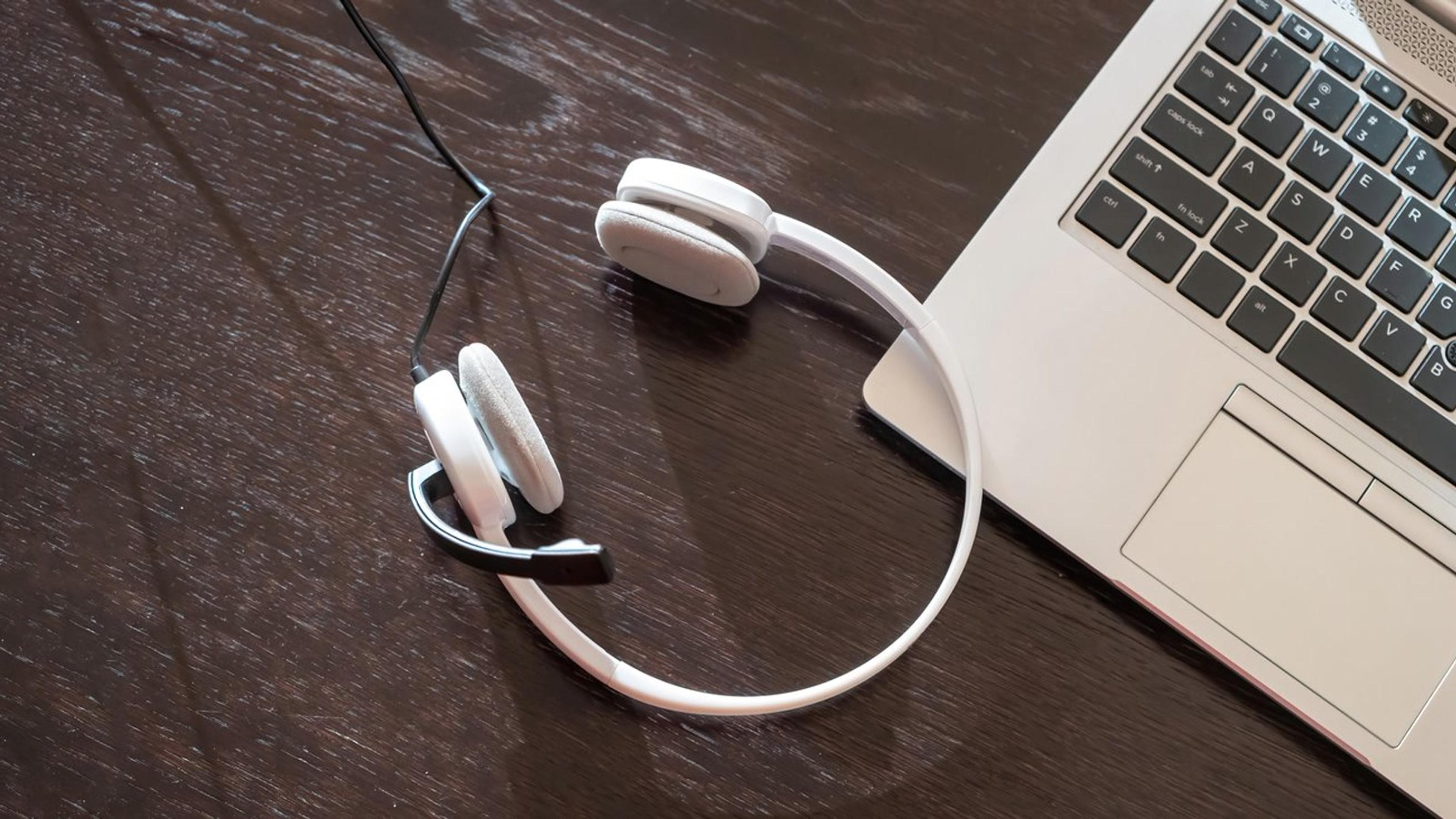 Headset and laptop on a wooden table — remote team communication tools